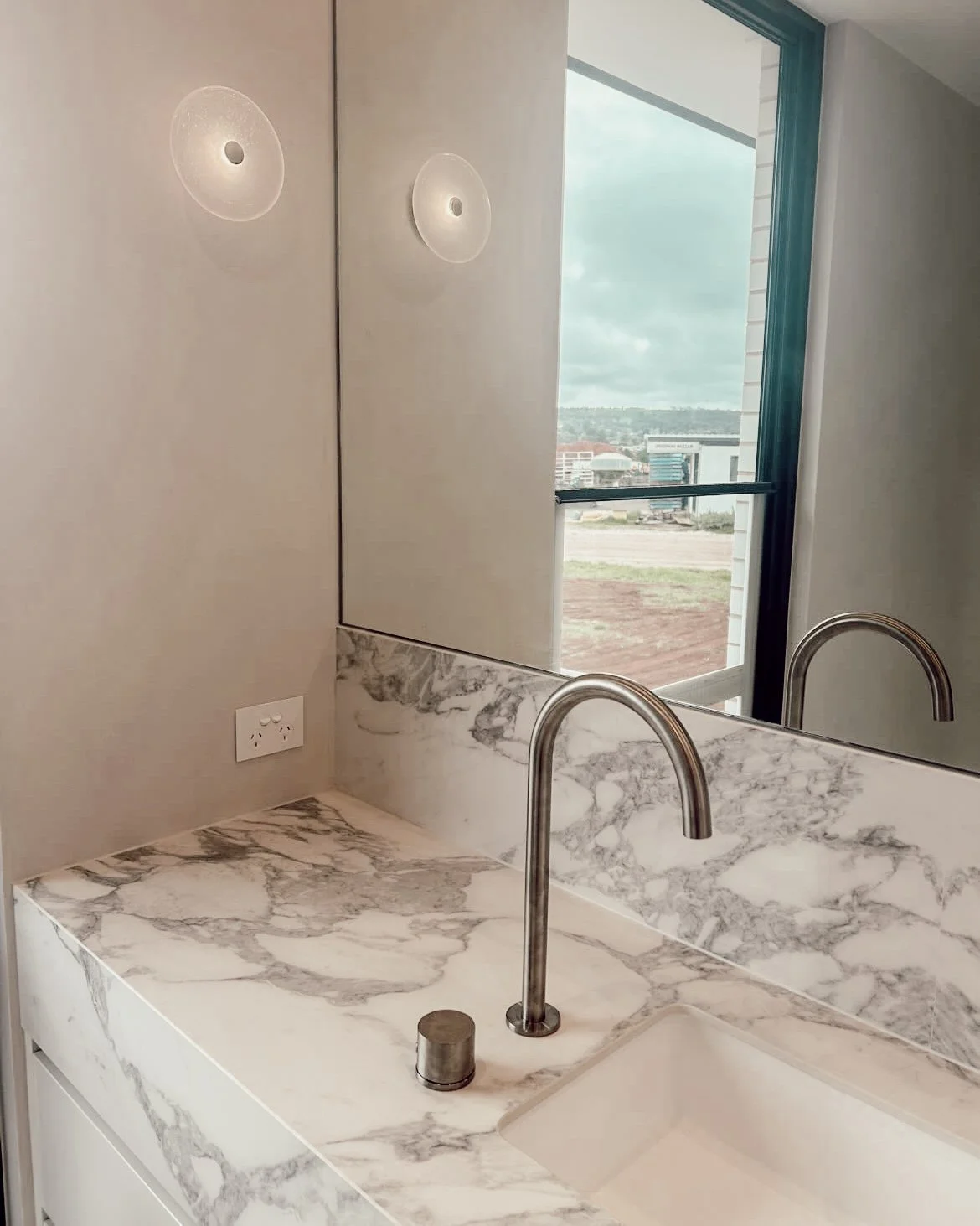 Soft minimal ensuite design in Sydney featuring a curved shower wall, brushed nickel tapware and warm neutral finishes by TID Studio
