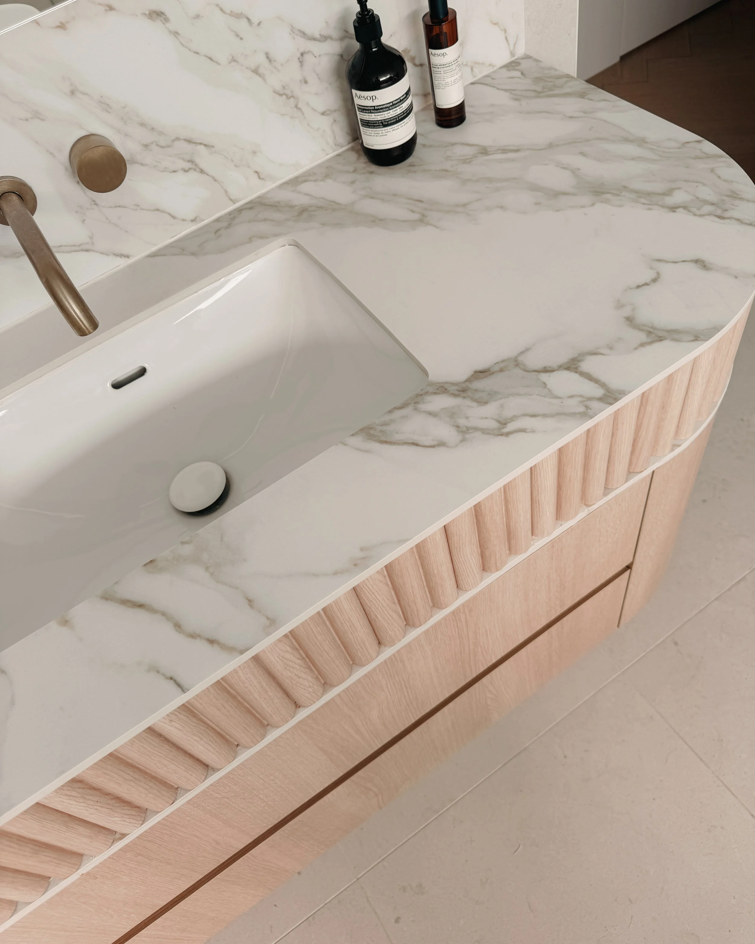 Modern bathroom custom curved vanity, and warm timber tones, fluted timber detail — coastal apartment in Gold Coast designed by TID Studio Sydney