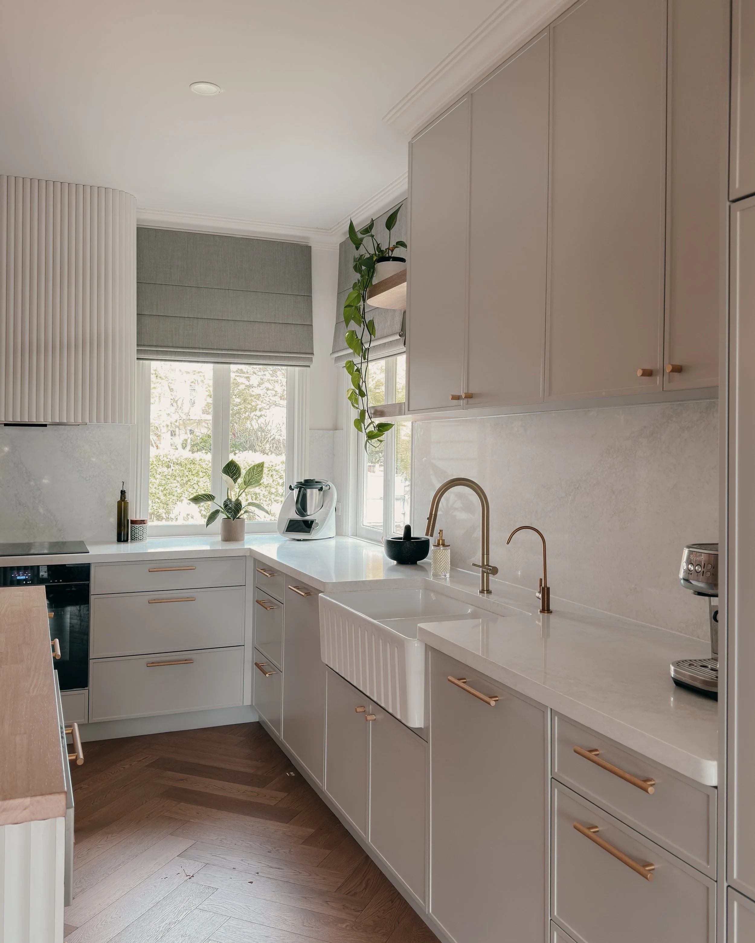 Modern Brisbane kitchen design with curved island, warm timber tones and integrated appliances, soft greige cabinetry, reeded detailing and brass tapware. Interior designer in Sydney