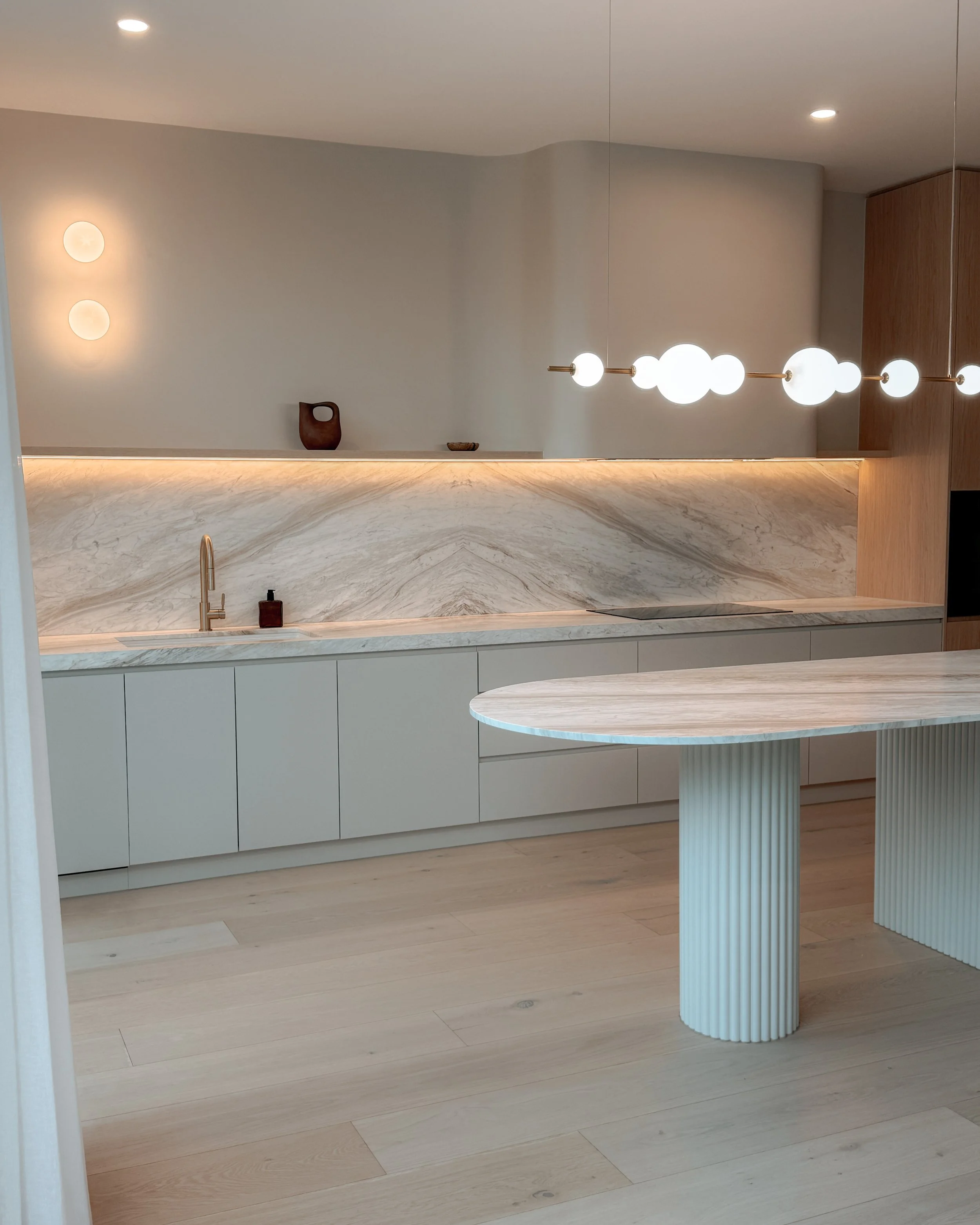 Contemporary soft-curved kitchen with fluted island, light timber cabinetry, and sculptural rangehood in a minimal-luxe Melbourne new-build. Designed by TID Studio, interior design in Sydney
