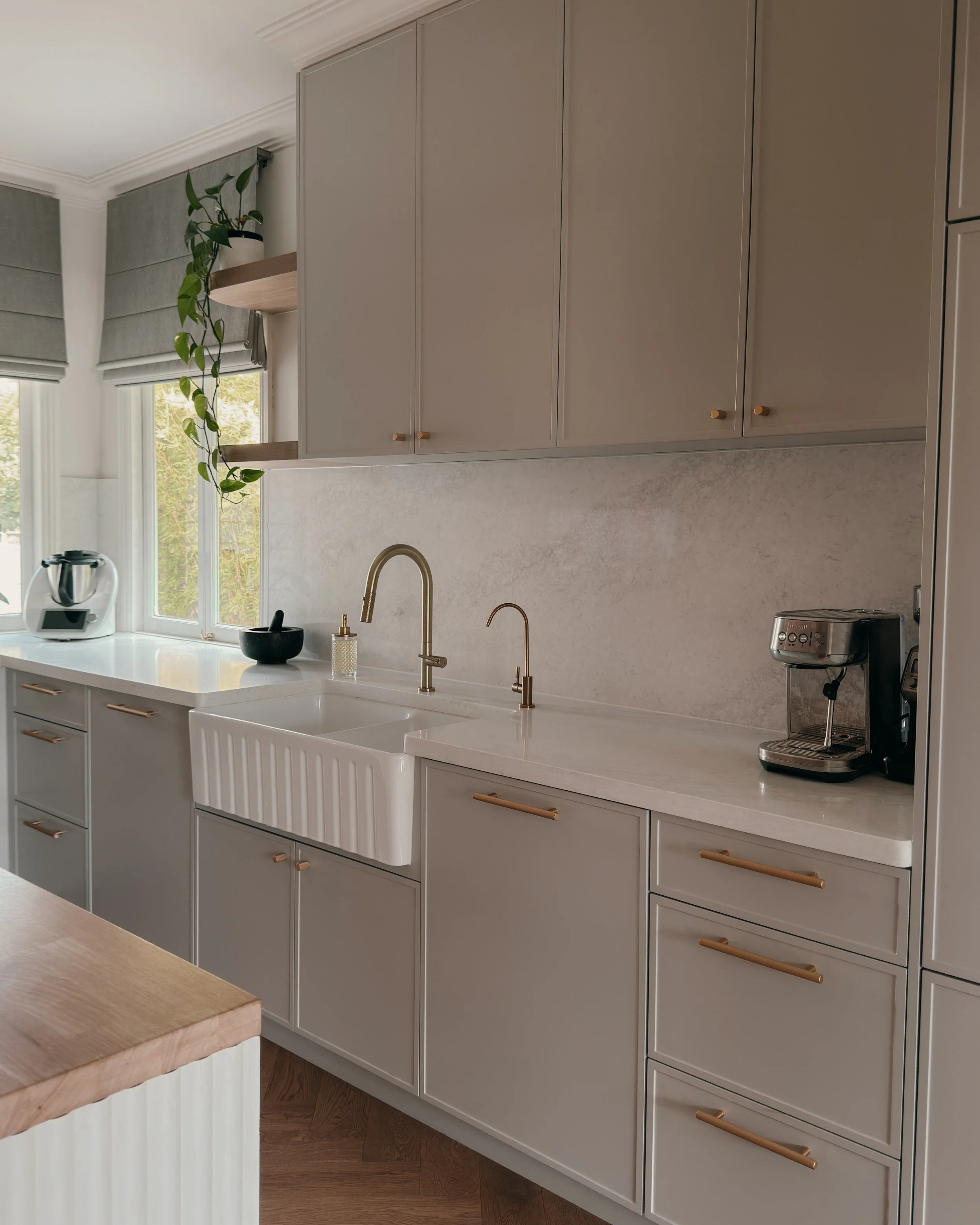 Modern Brisbane kitchen design with curved island, warm timber tones and integrated appliances, soft greige cabinetry, reeded detailing and brass tapware. Interior designer in Sydney