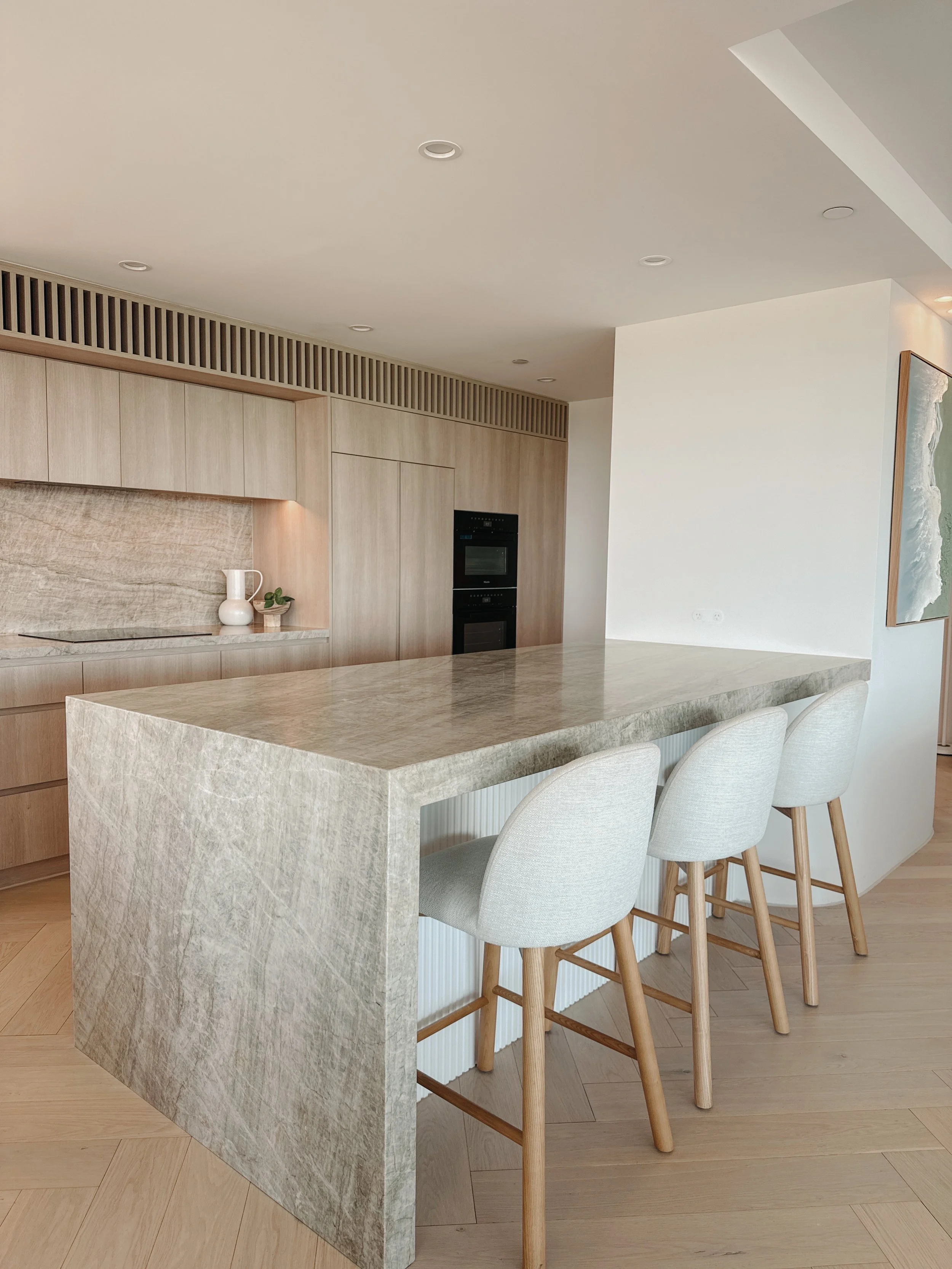 Contemporary coastal kitchen with curved island and pale timber cabinetry in Oceanview Apartment Gold Coast