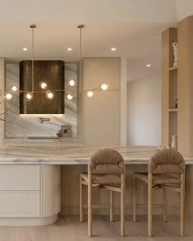 Modern luxury kitchen featuring Taj Mahal stone curved island, warm oak cabinetry, bronze rangehood and custom pantry design