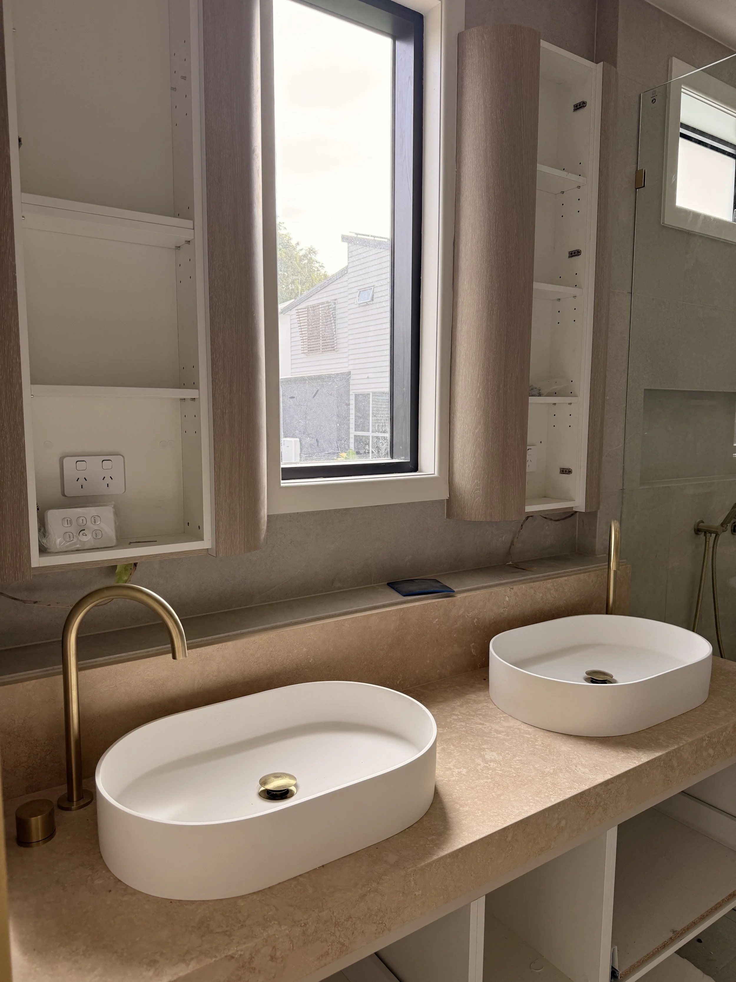 Modern master bathroom featuring curved vanity, travertine textures and brushed brass fixtures — Auriga Residence by TID Studio, interior designer Sydney