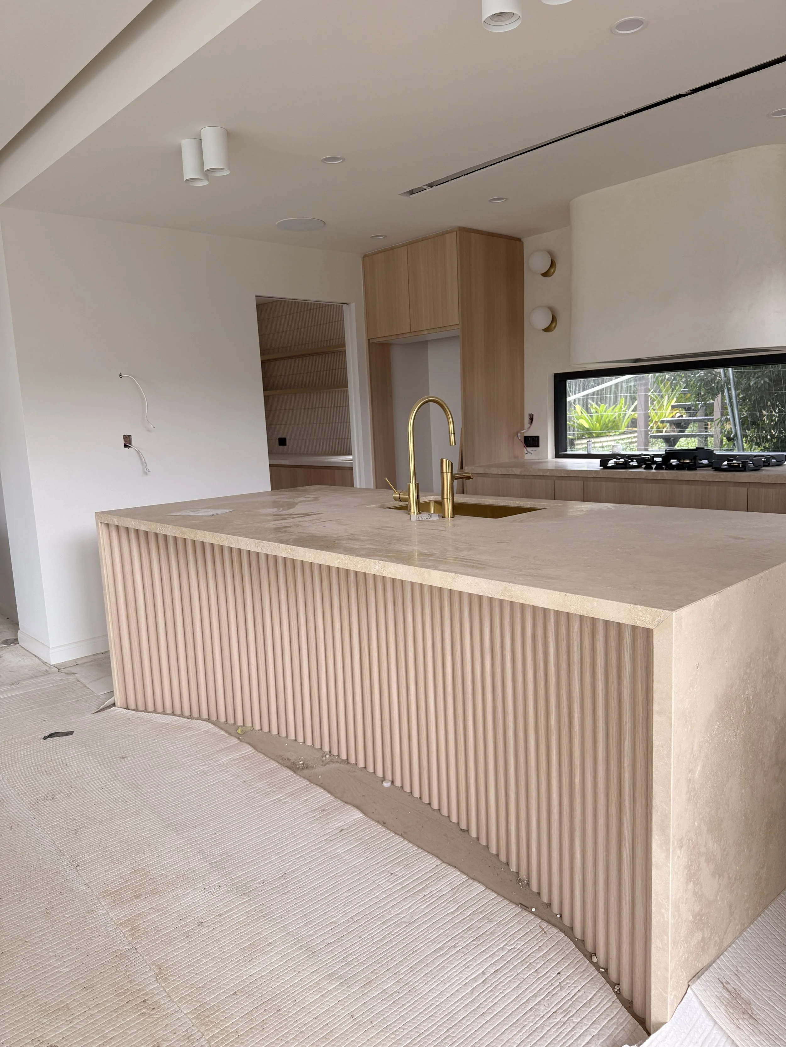 Modern coastal kitchen featuring a curved stone island, light timber cabinetry and neutral palette — Auriga Residence by TID Studio, interior designer Sydney
