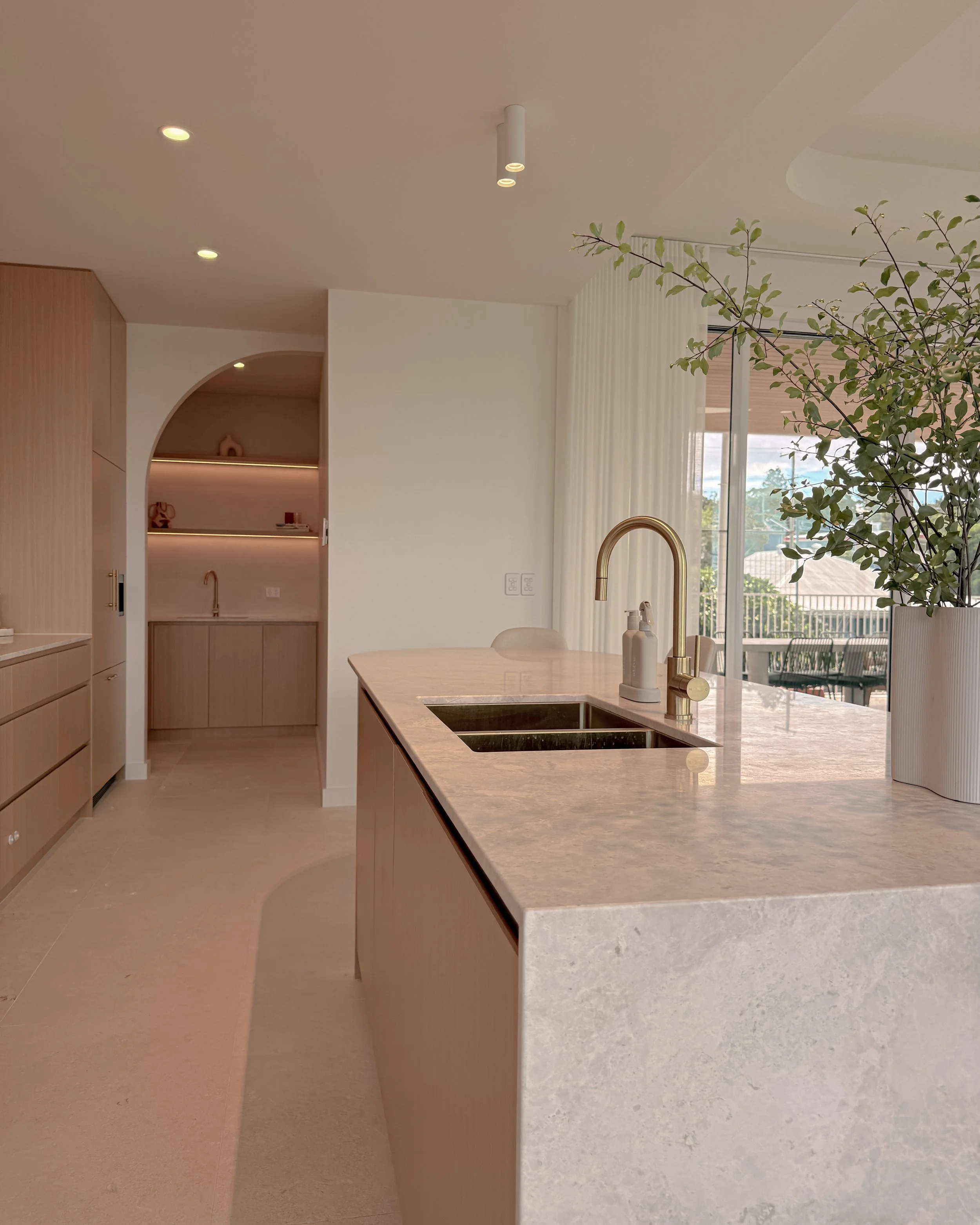 Modern coastal kitchen and pantry designed by TID Studio. Contemporary kitchen with curved cabinetry and fluted stone kitchen island. Sydney interior designer