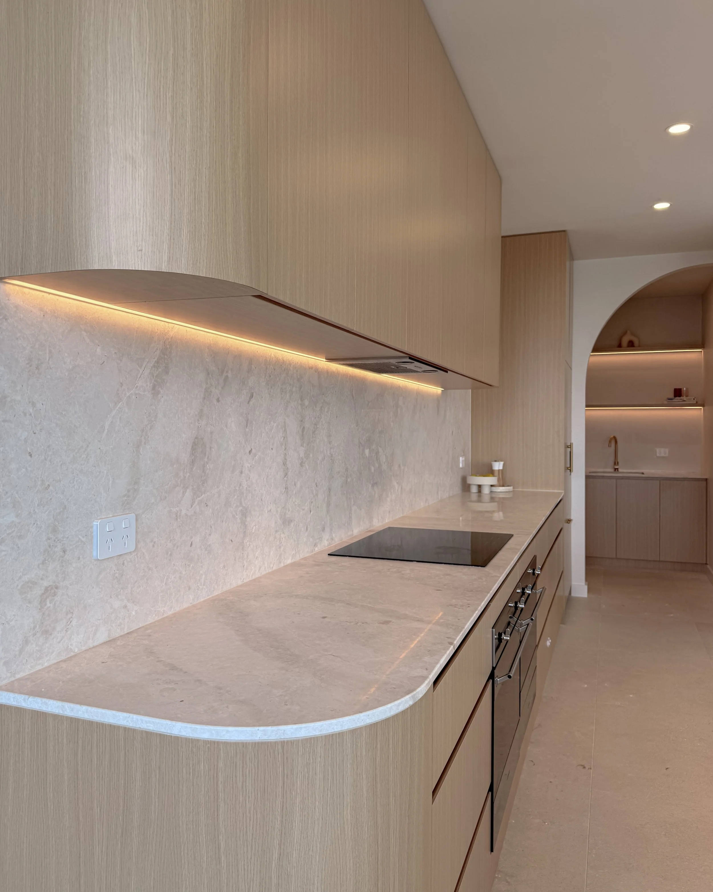 Modern coastal kitchen and pantry designed by TID Studio. Contemporary kitchen with curved cabinetry and fluted stone kitchen island. Sydney interior designer