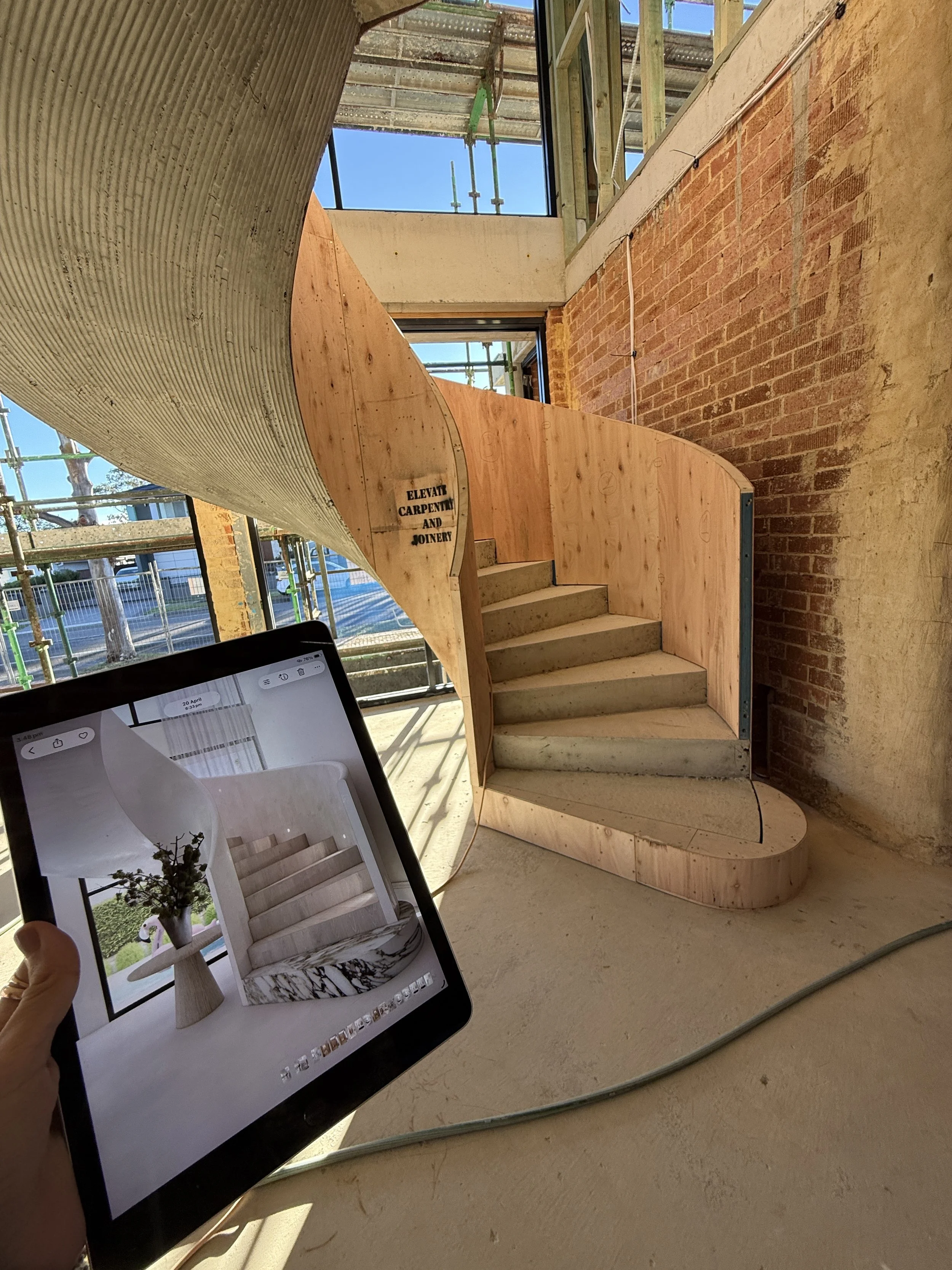 Contemporary living room with marble fireplace, curved staircase, and oversized neutral seating in a Sydney new-build
