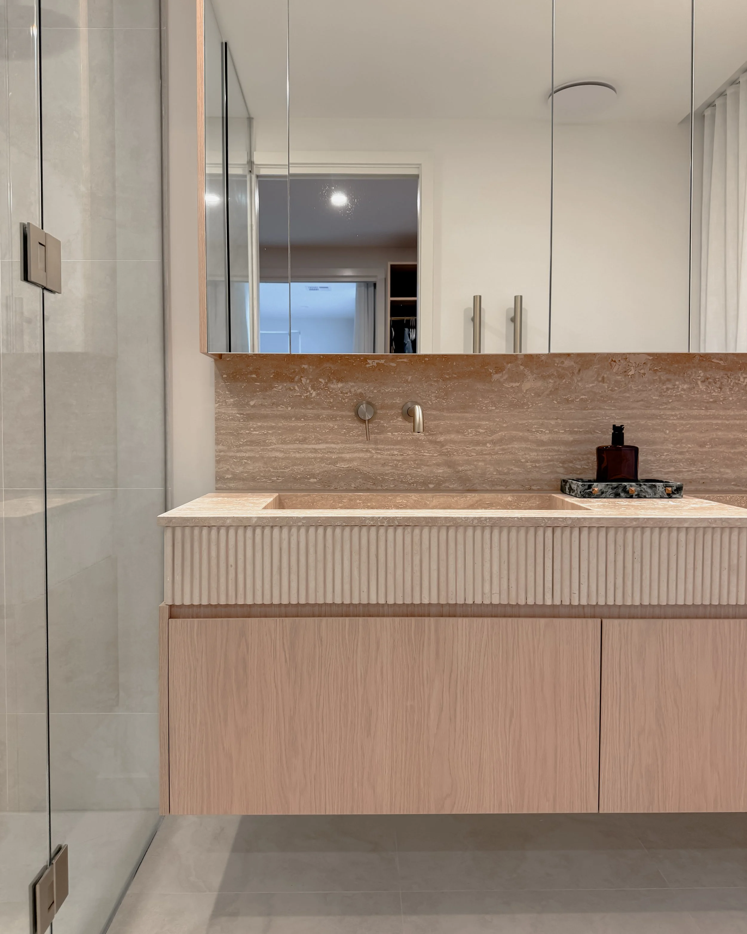 Contemporary Master Ensuite with custom stone sink, fluted travertine, double vanity, double shower in Melbourne new-build. Designed by TID Studio, interior design in Sydney