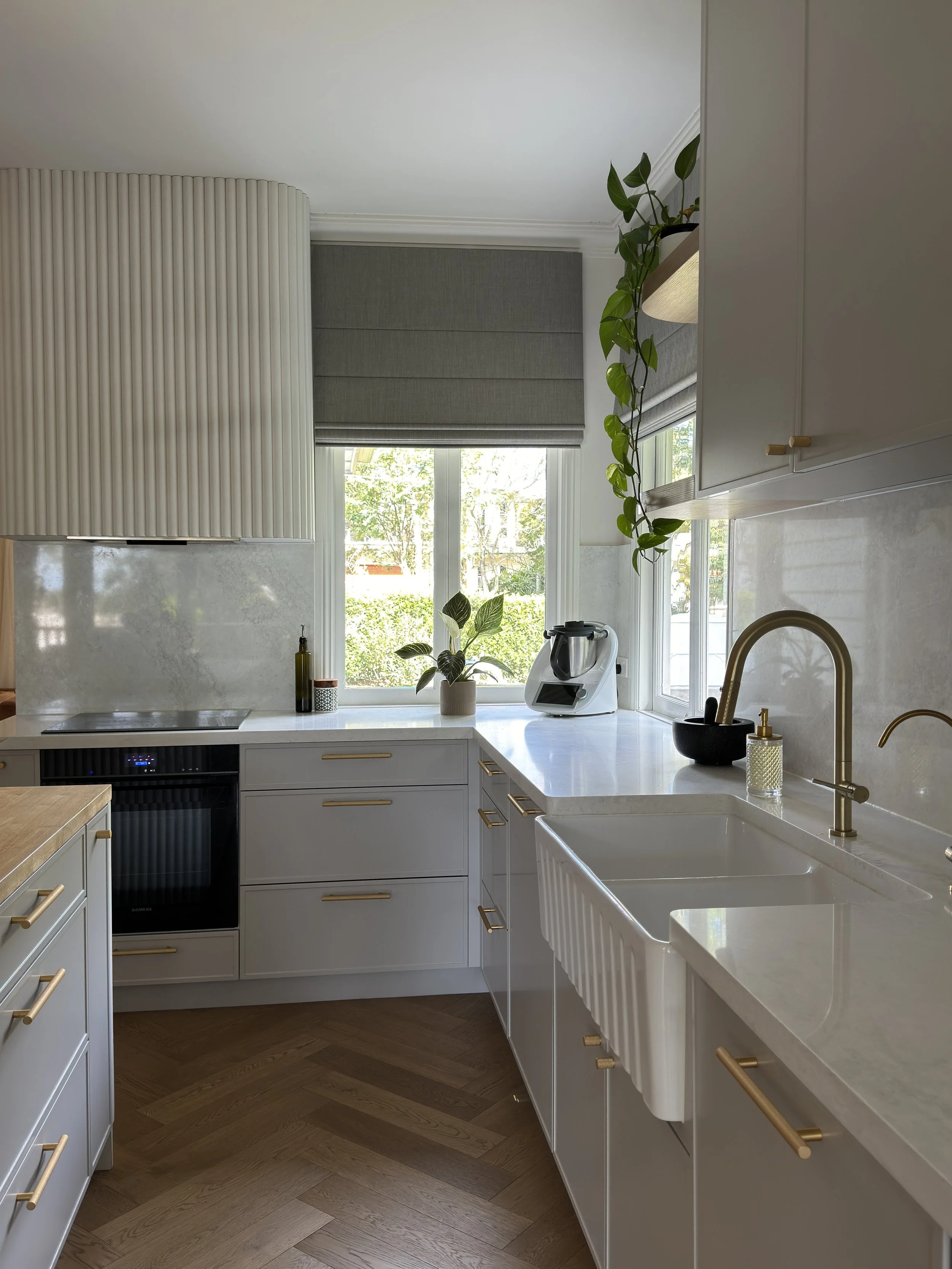 Modern Brisbane kitchen photo showing curved island, warm timber tones and integrated appliances