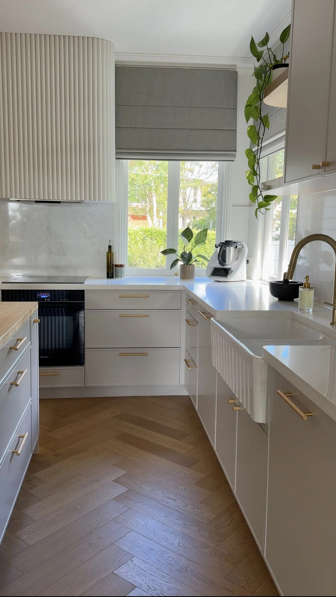 Detailed kitchen view with farmhouse sink and soft neutral stone benchtop