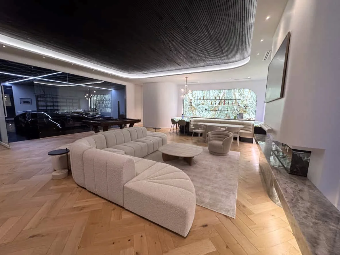 Soft neutral pool house with custom curved backlit bar and island with integrated banquette, modular sofa with fireplace anchored by stone benchseat on the sides, and warm minimal styling designed by TID Studio in Sydney