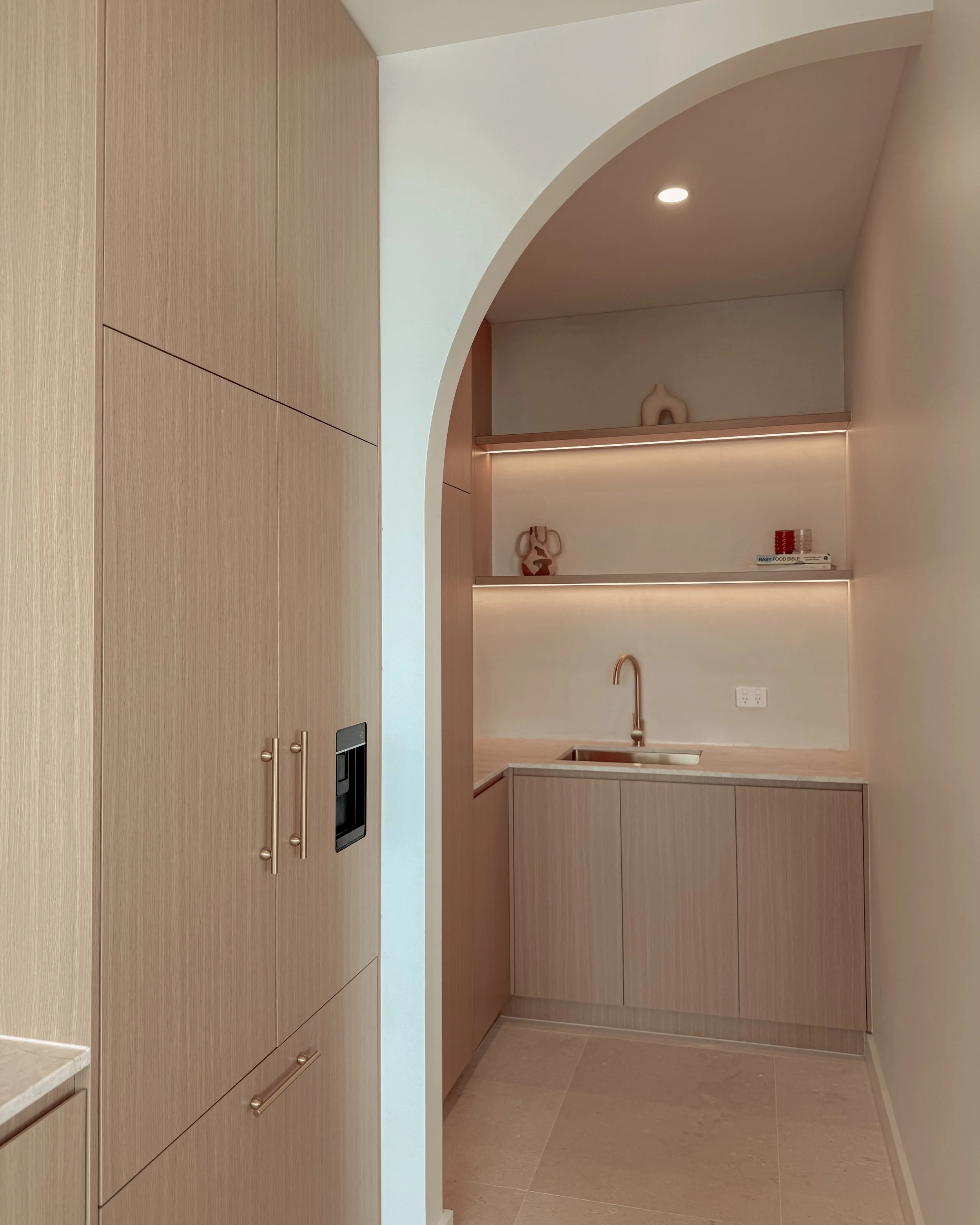 Modern coastal kitchen and pantry designed by TID Studio. Contemporary kitchen with curved cabinetry and fluted stone kitchen island. Sydney interior designer