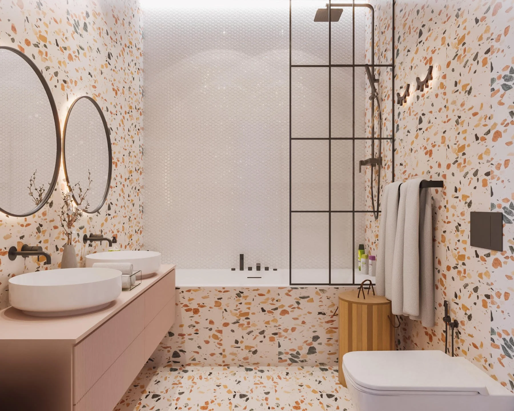 Kids’ bathroom with terrazzo tiles, round mirrors, pink vanity, and black-framed bath screen