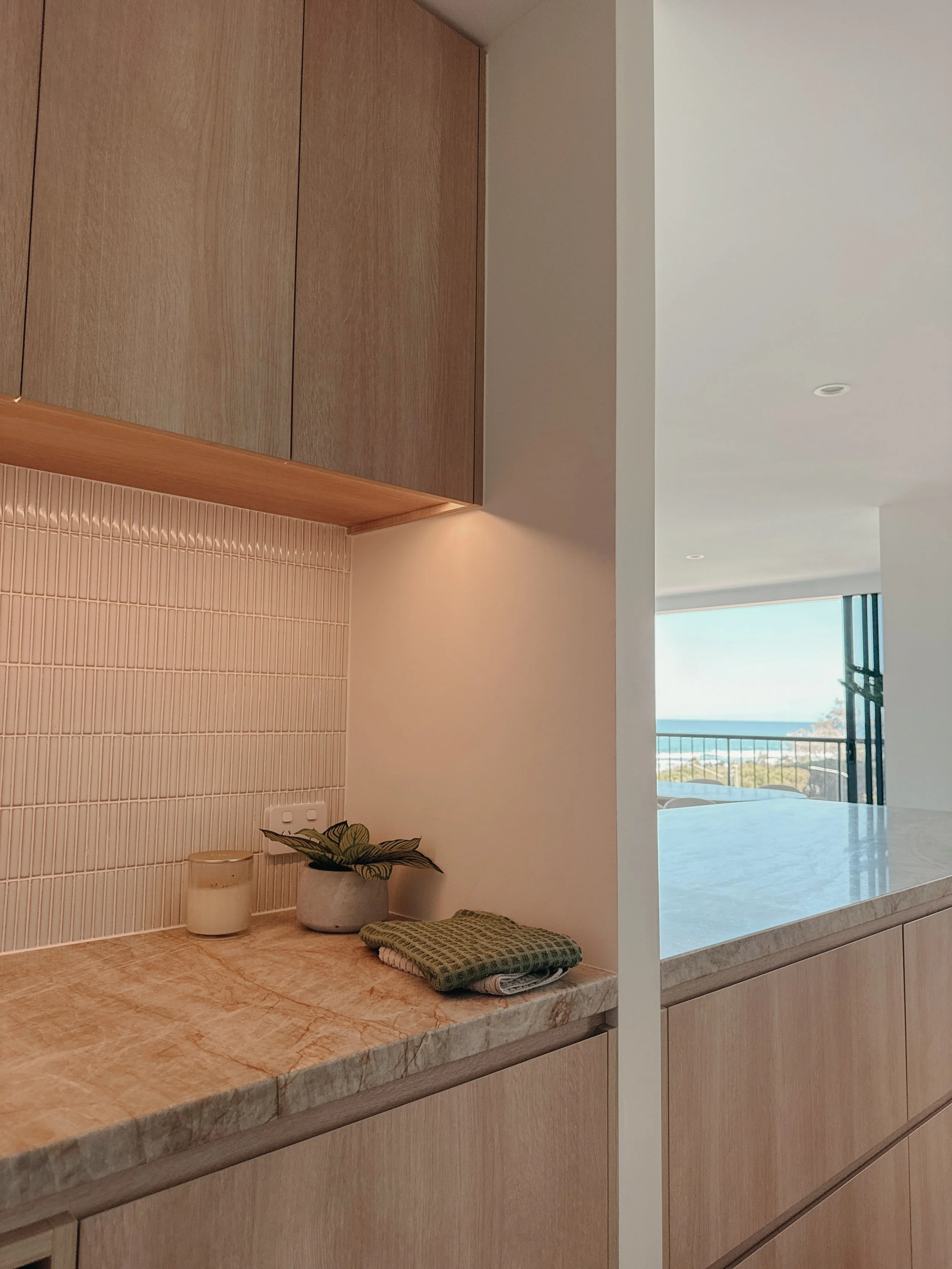 Soft neutral kitchen with ocean views and minimalist joinery by TID Studio