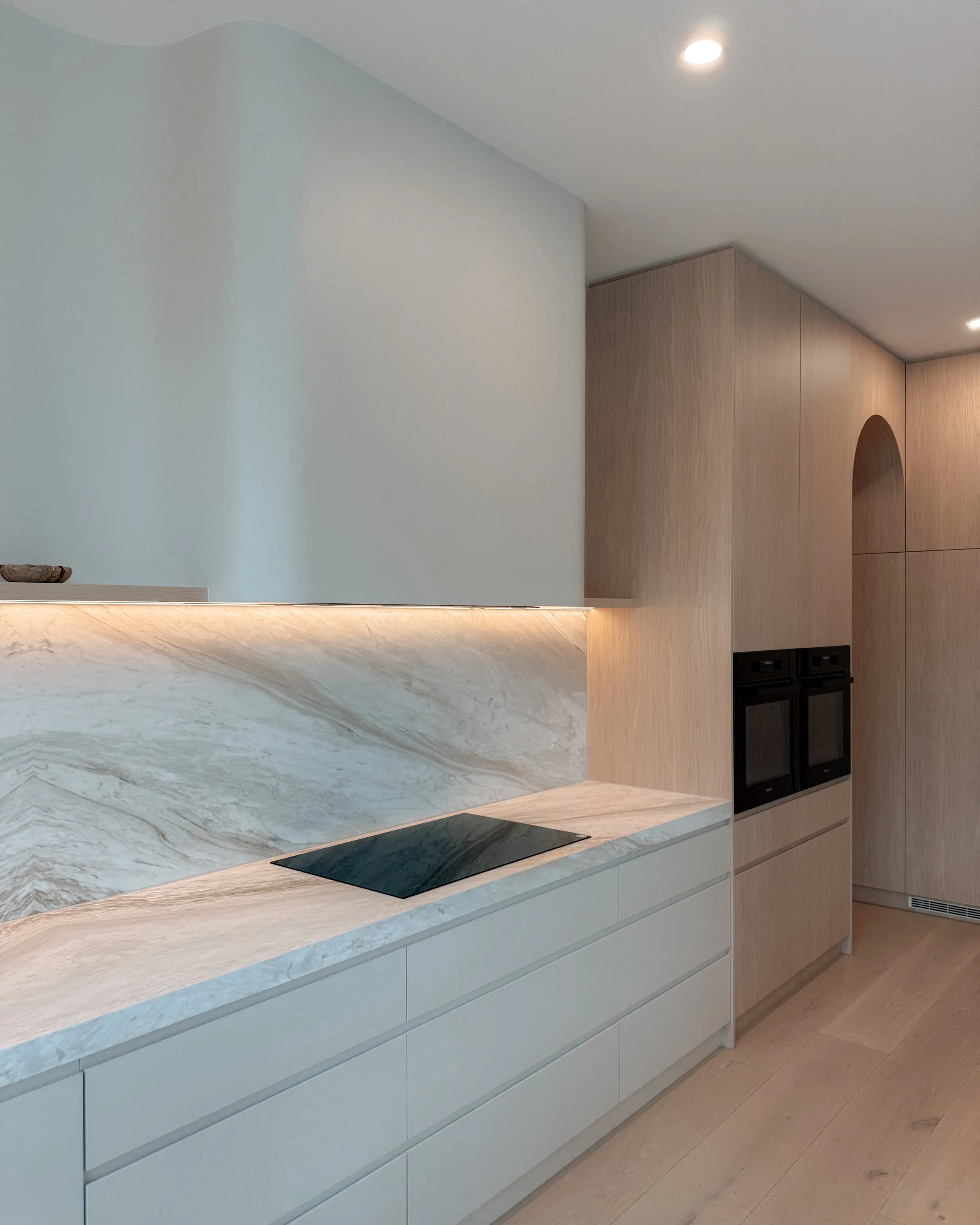 Contemporary soft-curved kitchen with fluted island, light timber cabinetry, and sculptural rangehood in a minimal-luxe Melbourne new-build. Designed by TID Studio, interior design in Sydney