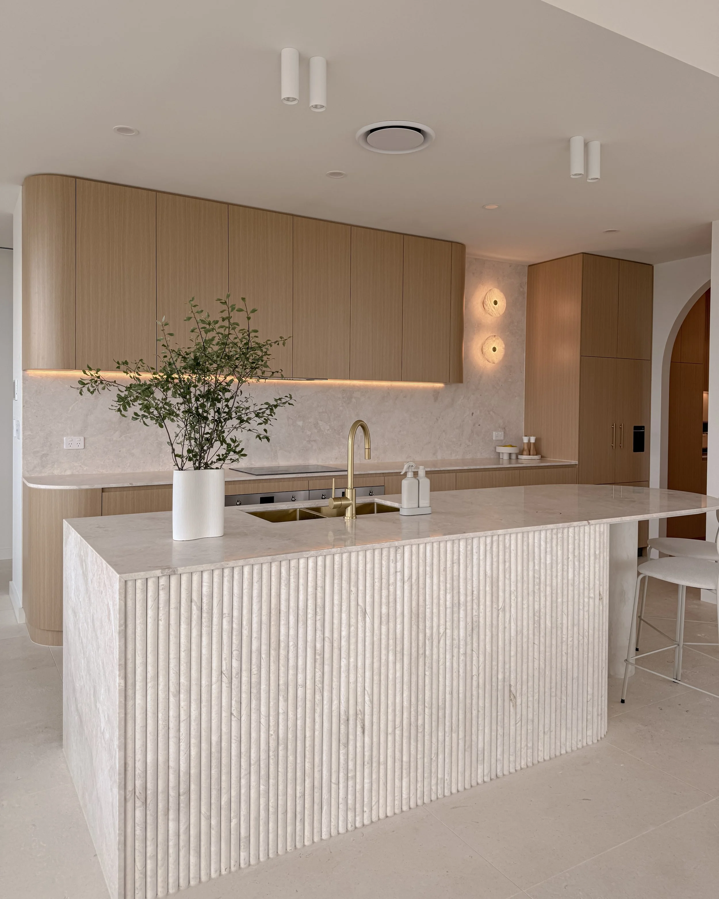 Modern coastal kitchen and pantry designed by TID Studio. Contemporary kitchen with curved cabinetry and fluted stone kitchen island. Sydney interior designer