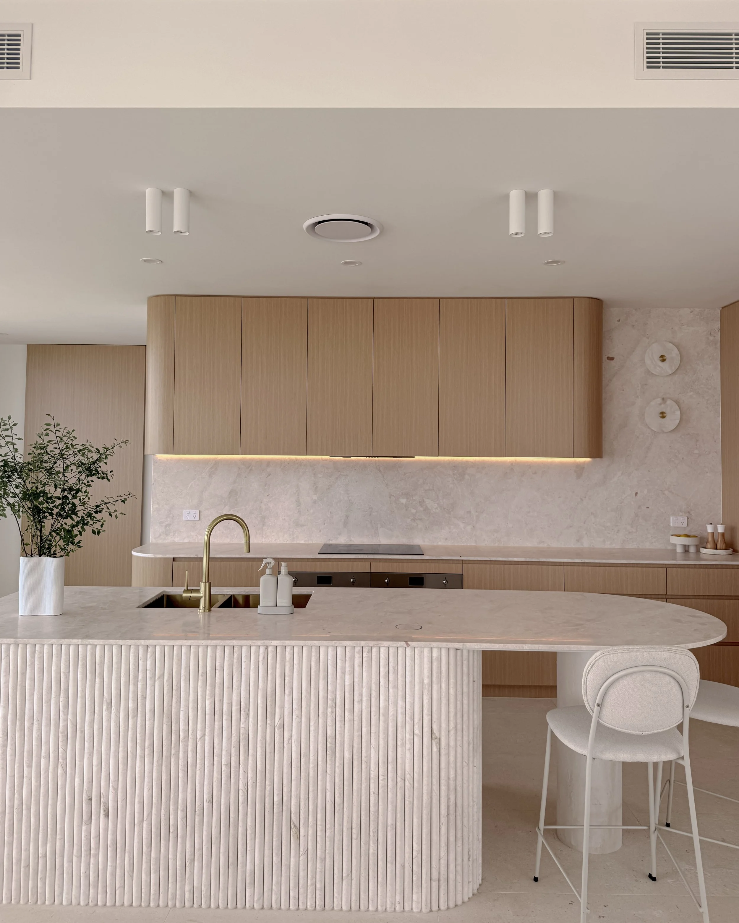Modern coastal kitchen and pantry designed by TID Studio. Contemporary kitchen with curved cabinetry and fluted stone kitchen island. Sydney interior designer