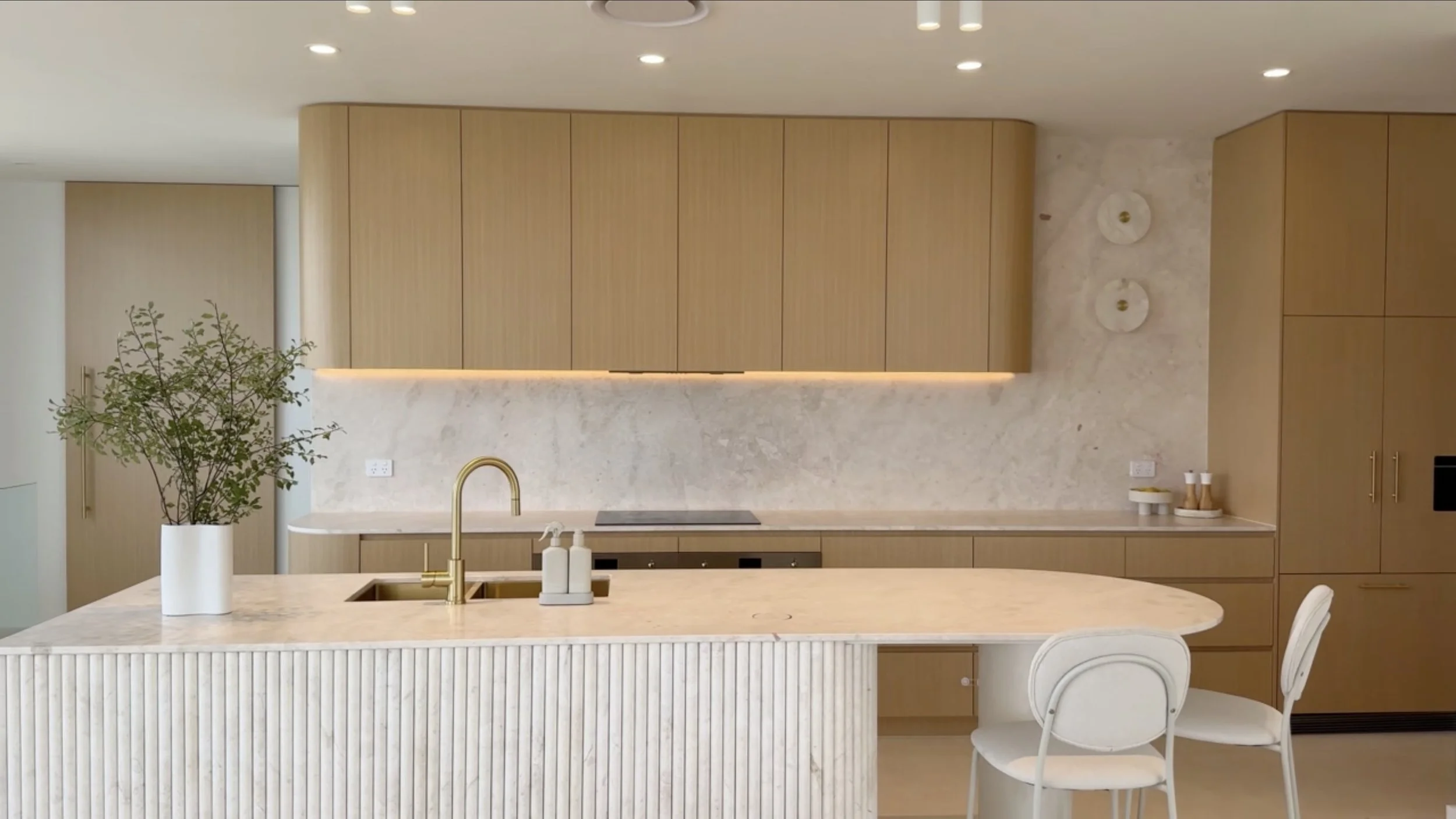 Coastal-inspired minimal kitchen with rounded overheads and stone island by TID Studio