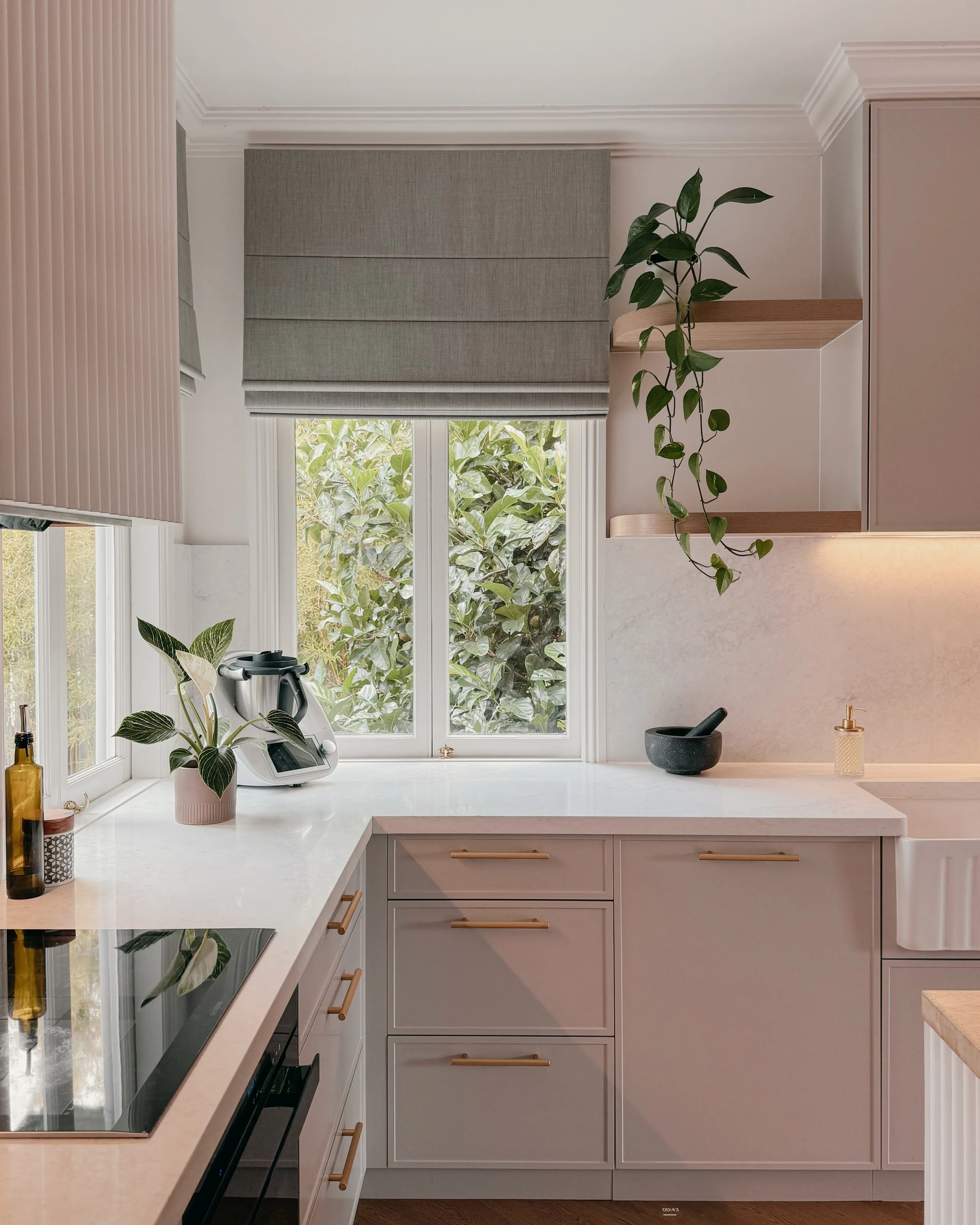 Modern Brisbane kitchen design with curved island, warm timber tones and integrated appliances, soft greige cabinetry, reeded detailing and brass tapware. Interior designer in Sydney