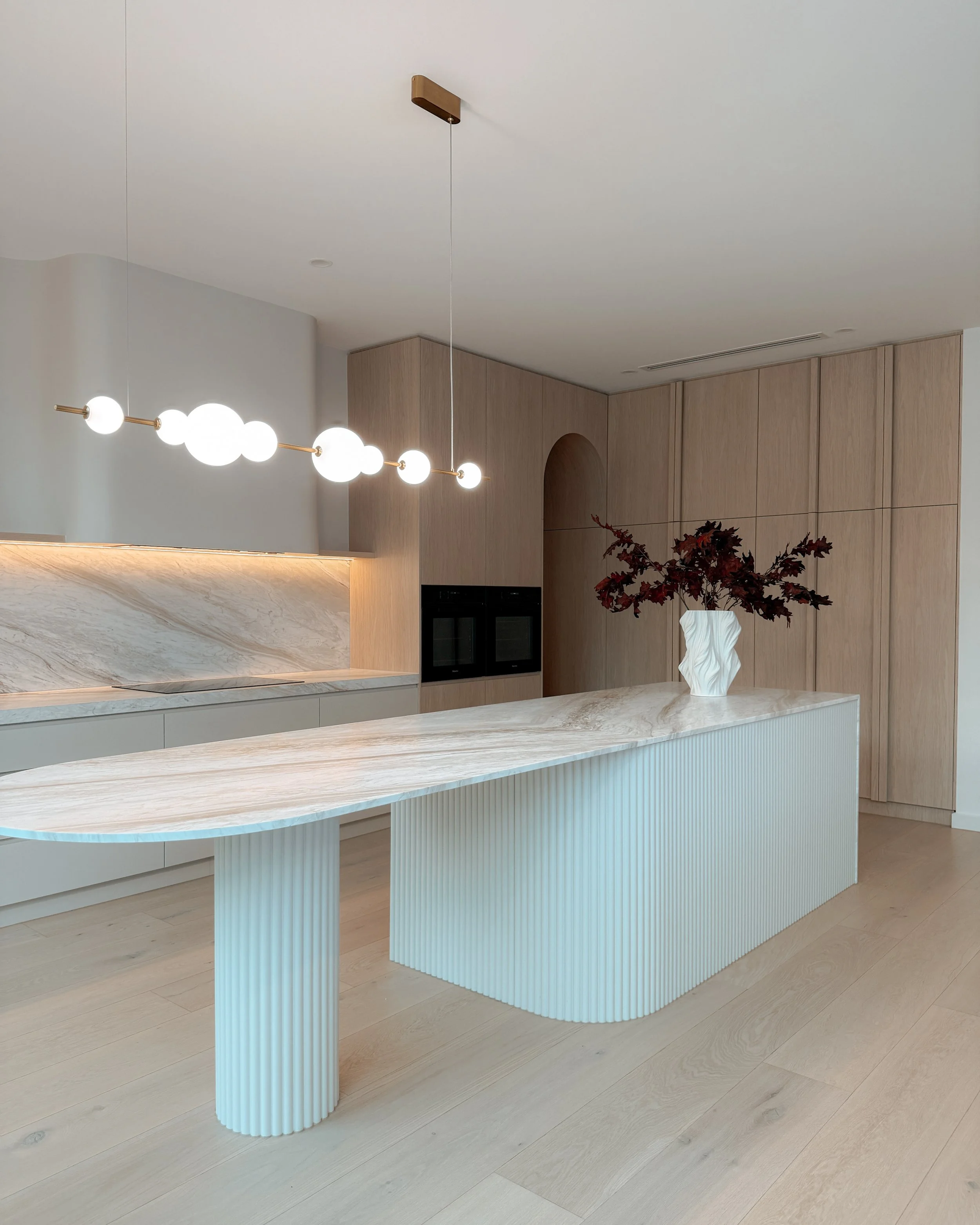 Contemporary kitchen with arched pantry entry and fluted island. New-build in Melbourne. TID Studio interior design in Sydney