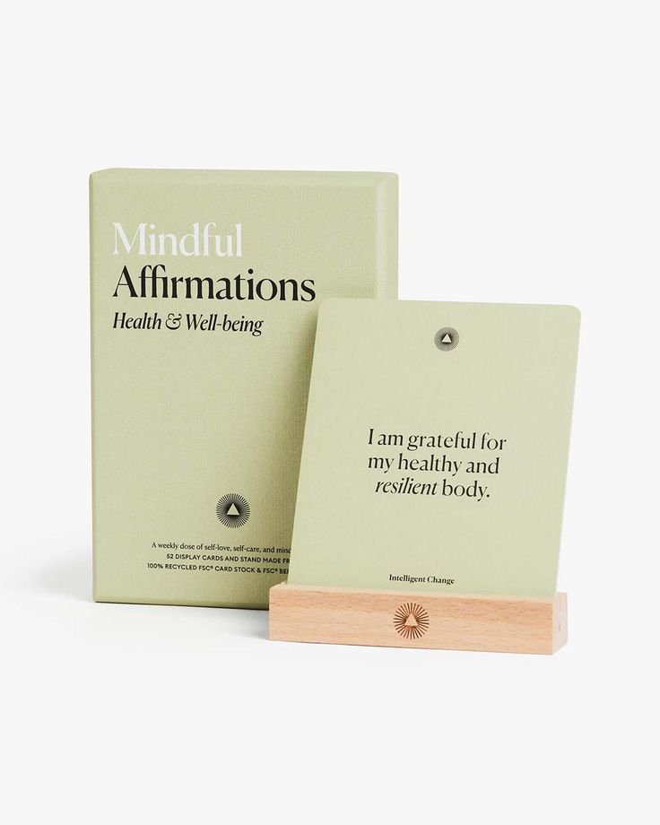 A set of mindfulness affirmation cards about health and well-being, with one card reading 'I am grateful for my healthy and resilient body,' displayed on a wooden stand, and a matching box behind it.