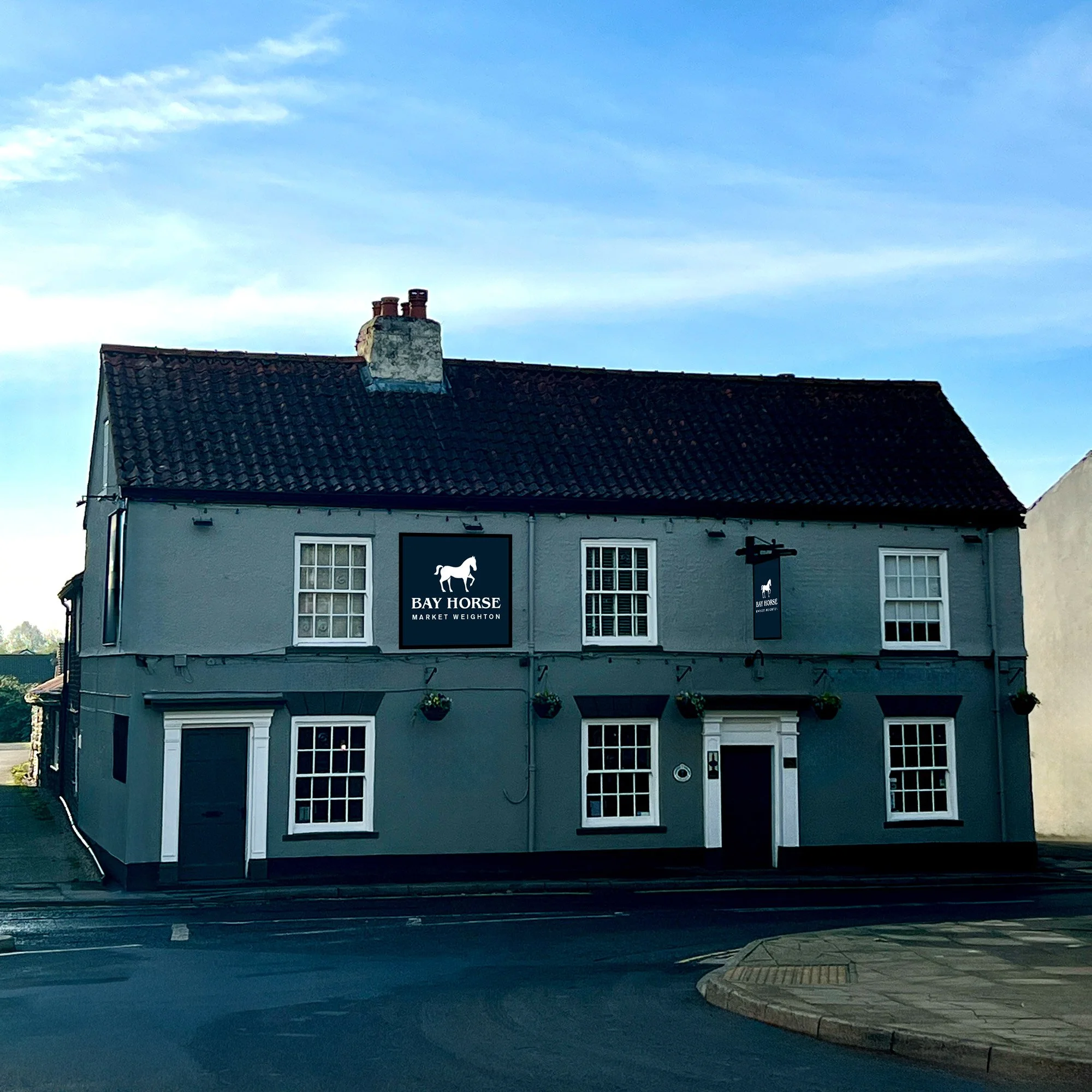 Exterior of The Bay Horse pub in Market Weighton, a traditional two-storey Yorkshire inn with hanging baskets and Bay Horse signage.