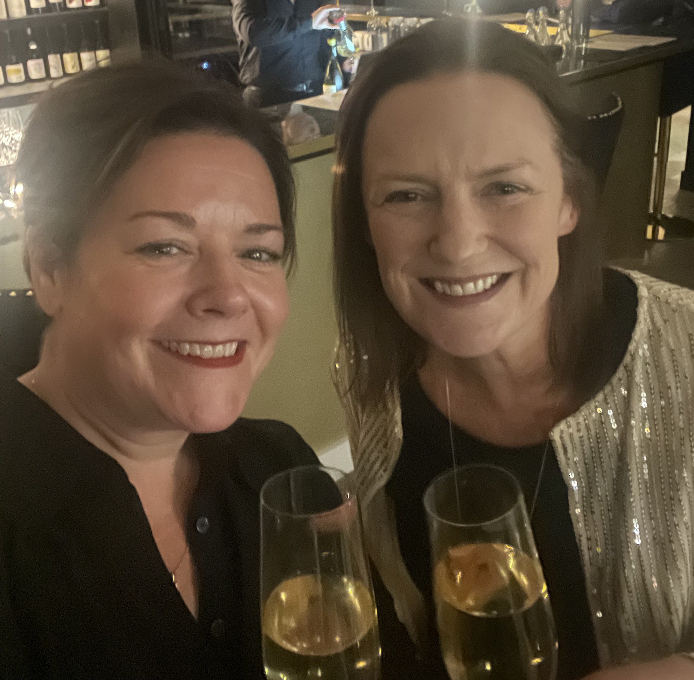 Claudia Pritchard and Jo Wehring with a glass of sparkling wine.