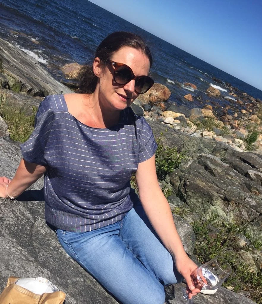 Jo Wehring at the beach holding a glass of wine.