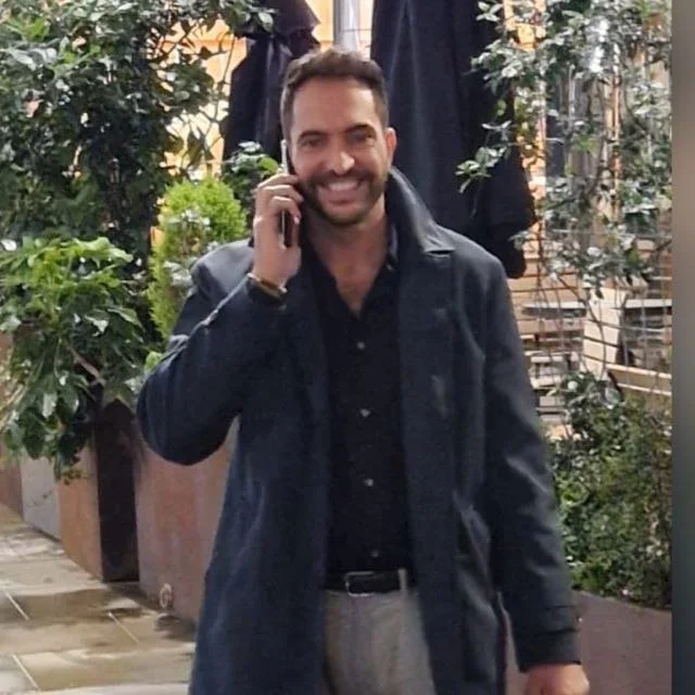Azzam Ibellini - Prime London Real Estate specialist with over 25 years experiencefor sale and sold azzam ibellini . pres. prime real services l. A smiling man with dark hair and beard, wearing a black jacket and black shirt, talking on a cell phone