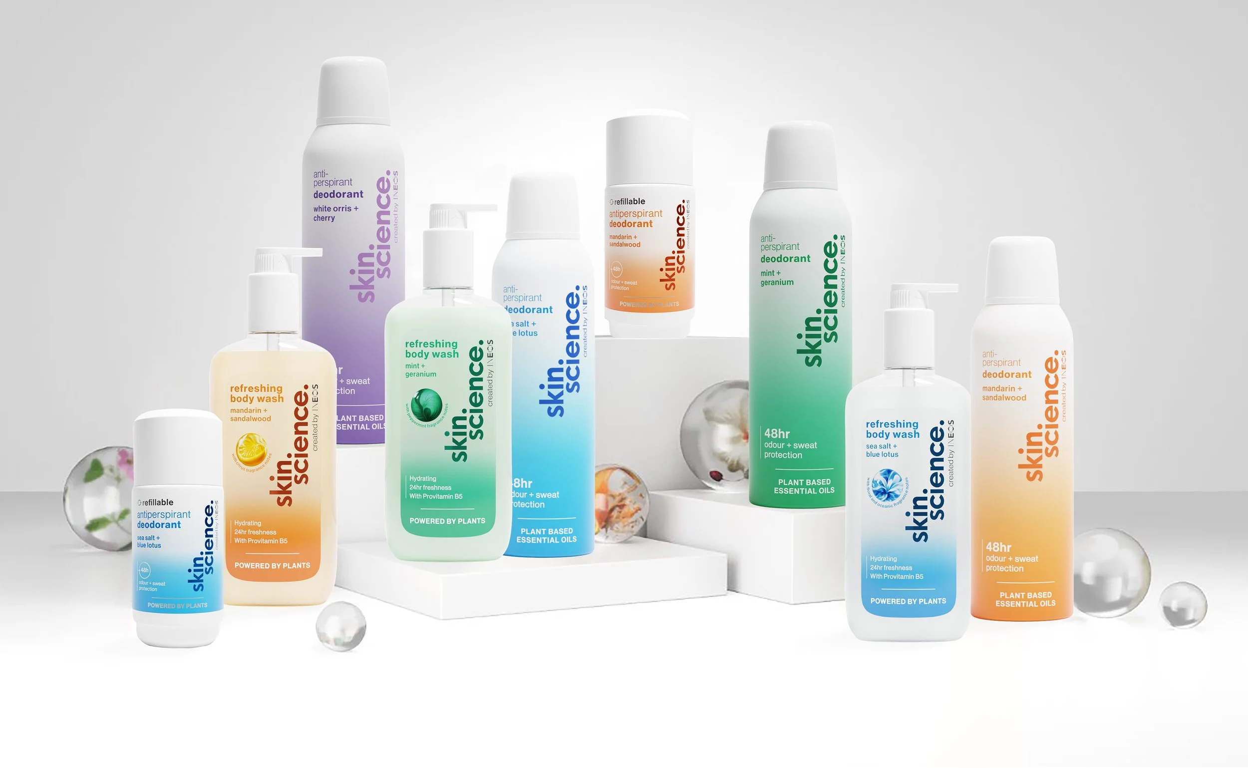 Collection of Skin Science deodorant and body wash products with white and transparent spheres for decoration on a white background.