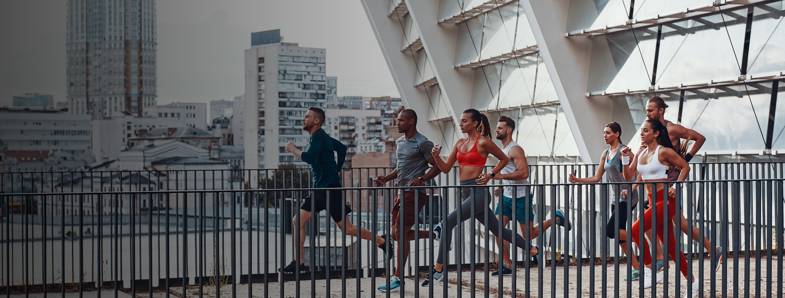 Group of people running on a rooftop, city skyline in the background