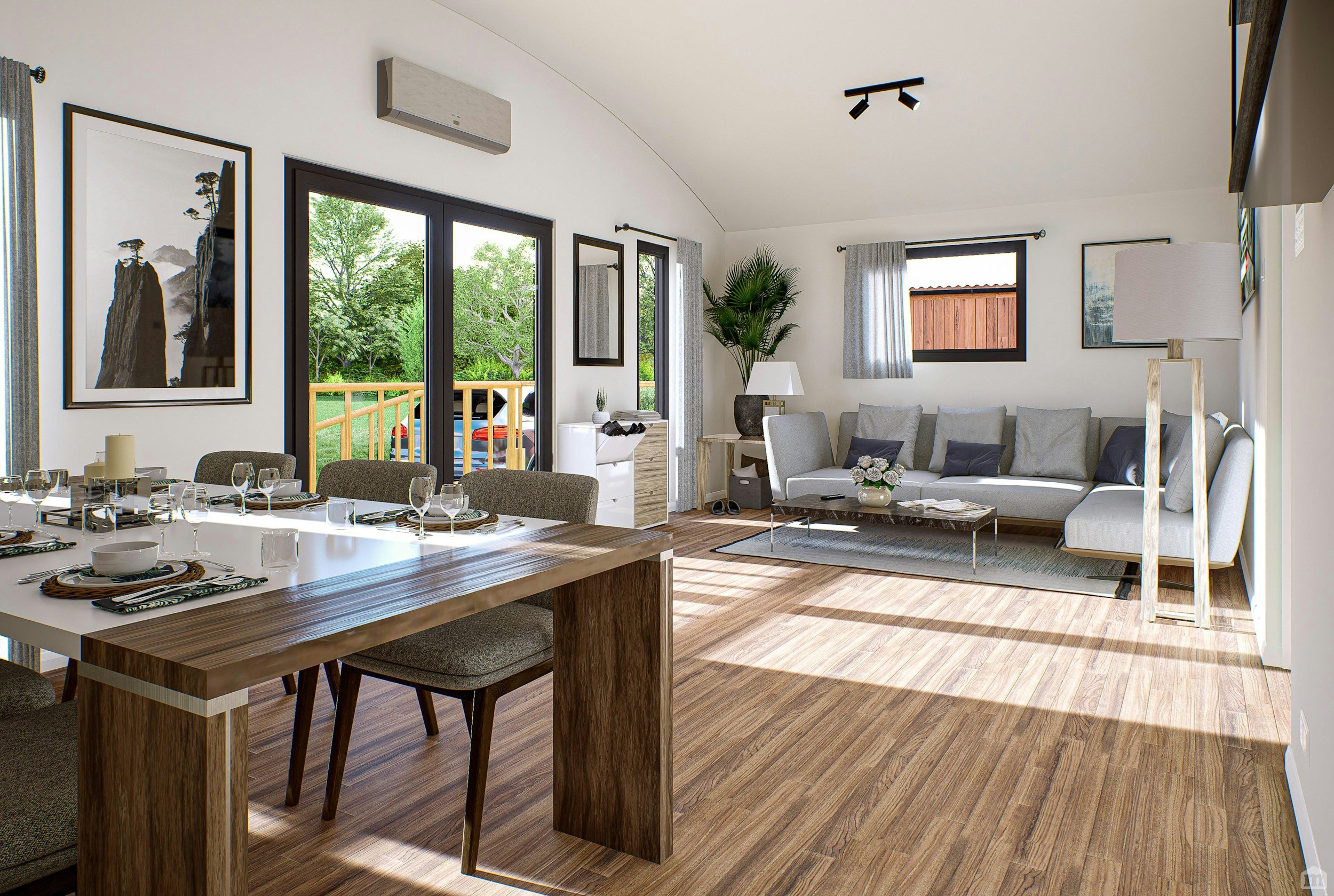 A living room and dining area with large windows, a gray sofa, a wooden dining table set with plates, glasses, and napkins, artwork on the walls, a potted plant, and a view of a backyard with green trees.