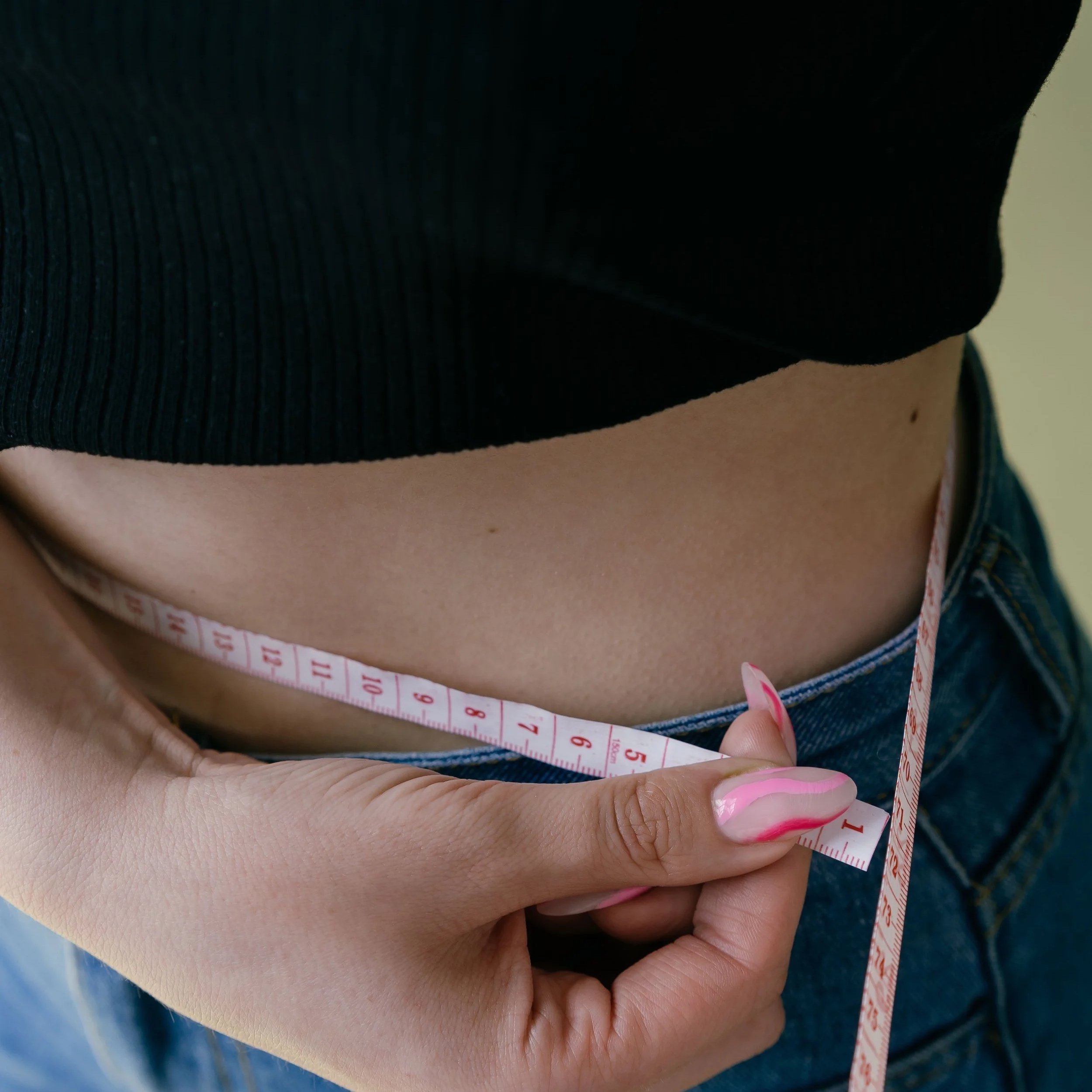 Person measuring their waist with a tape measure