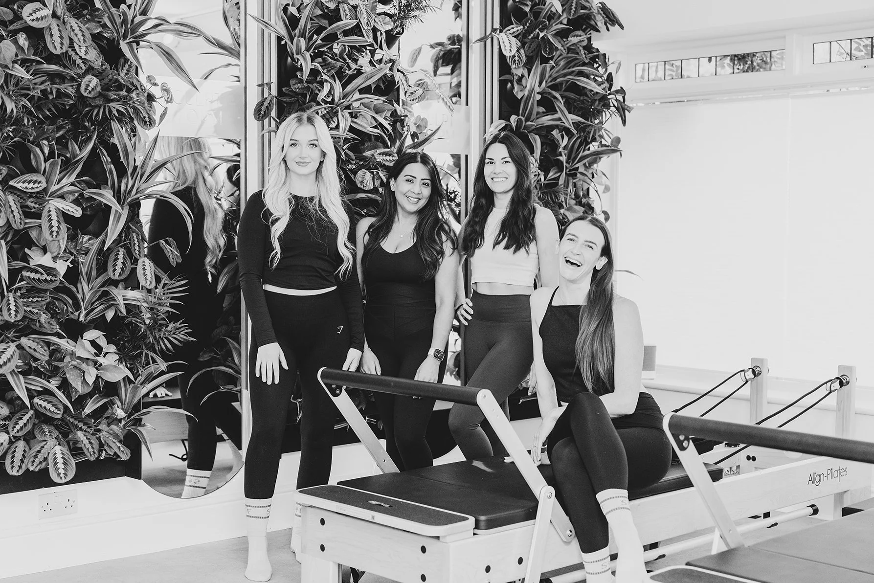 Four female wellness trainers standing inside Sculpt Form Studio smiling at the camera