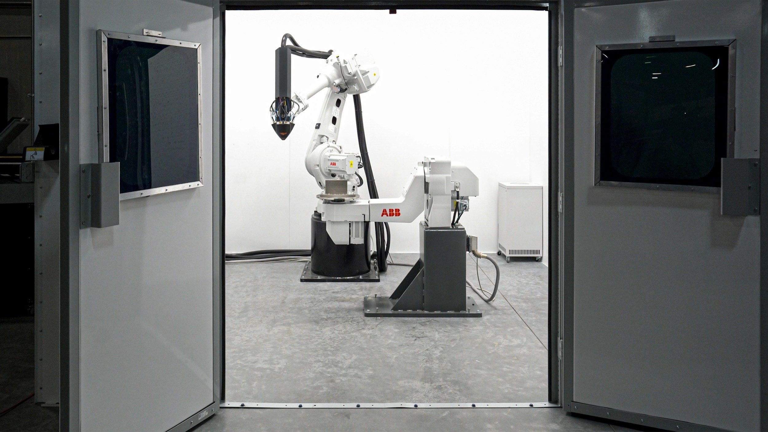 An industrial robotic arm inside a sealed white enclosure.