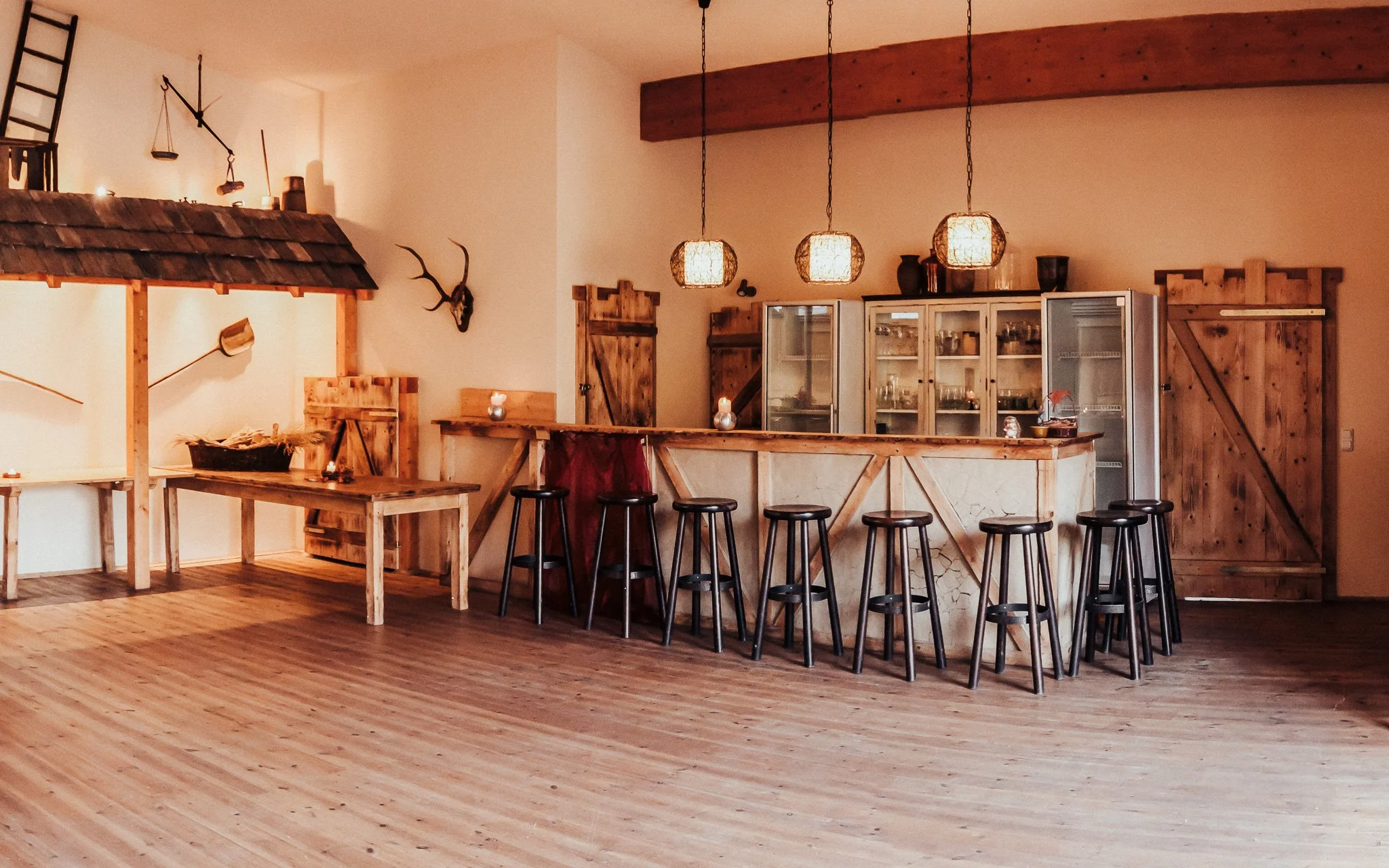 Gemütliche Bar mit Holztheke, schwarzen Barhockern, Holzschränken, rustikalen Wanddekorationen und warmem Licht