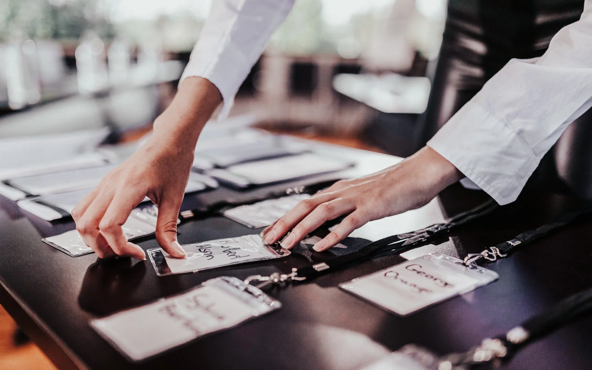 Person legt Namensschild auf einen Tisch mit weiteren Namensschildern bei einer Veranstaltung.