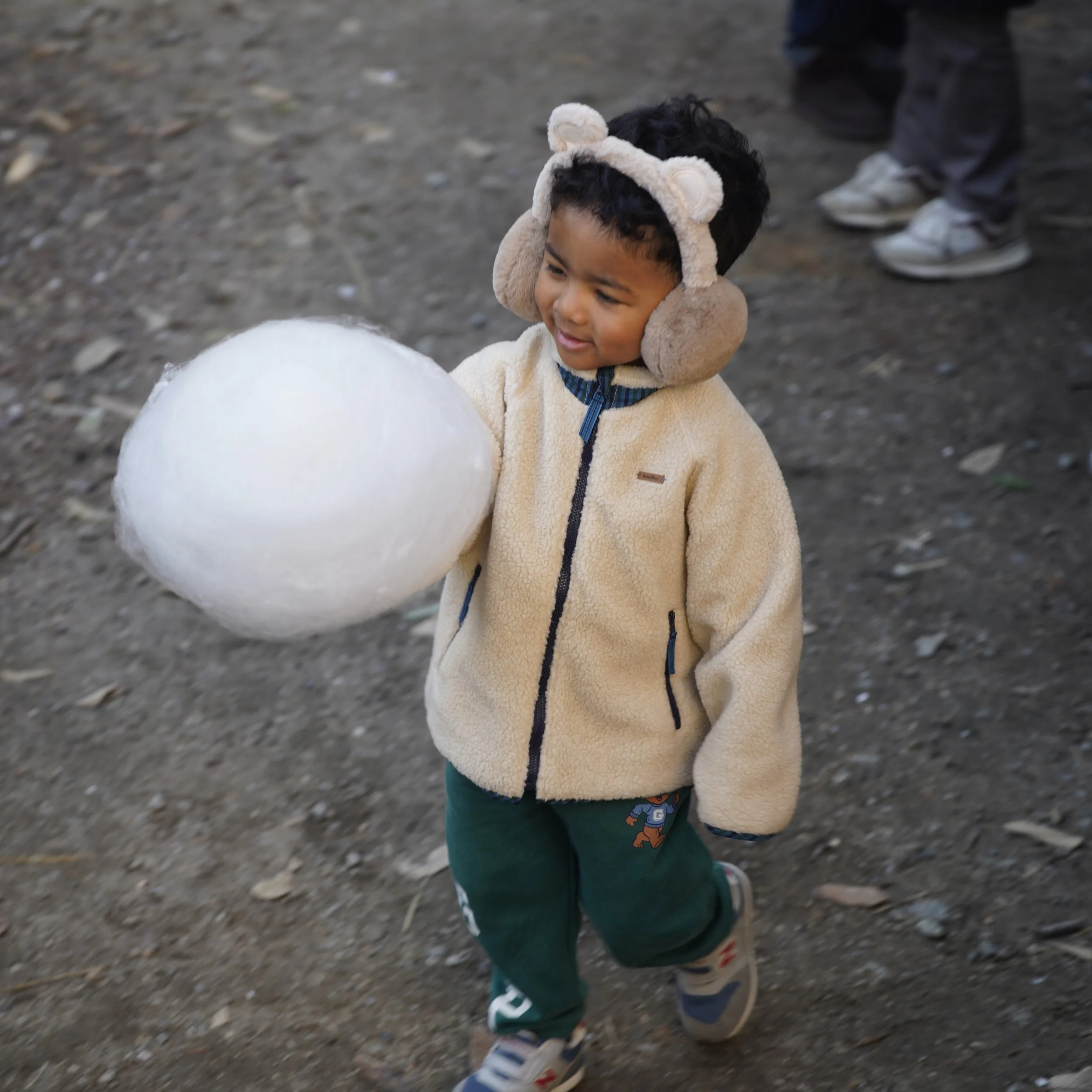 耳あてをした子供が雪玉を持っている
