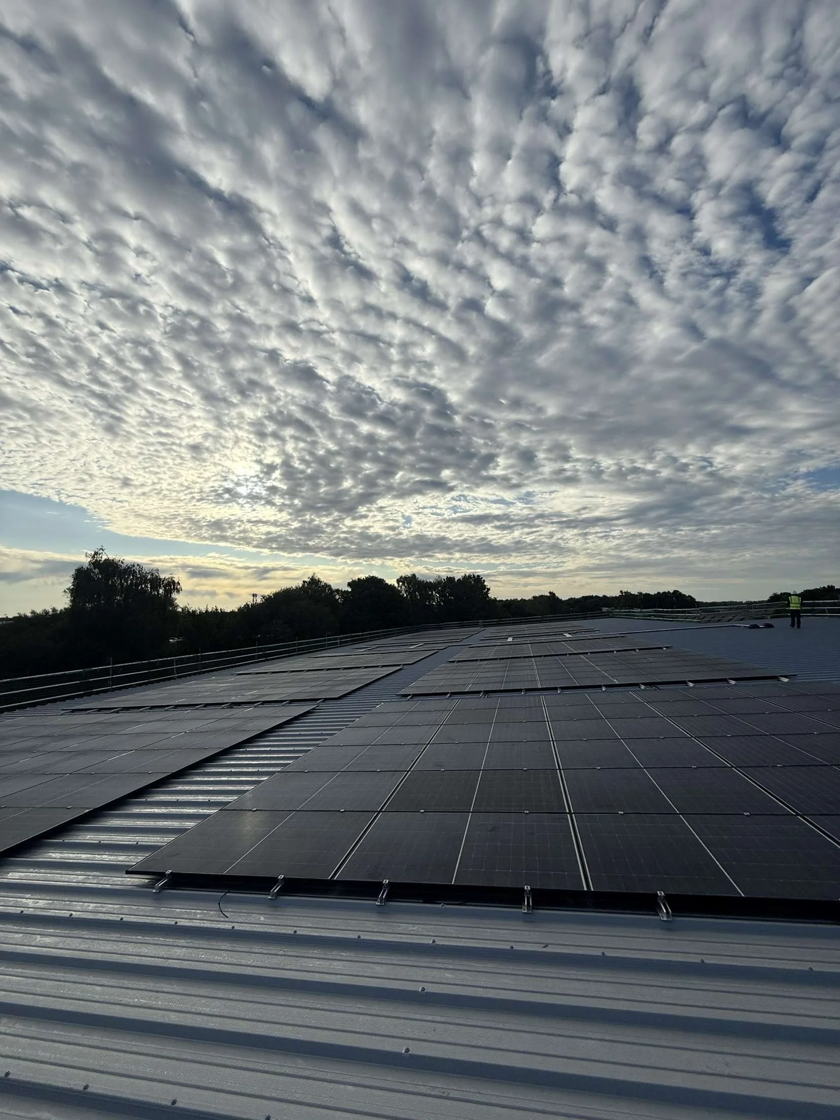 Solar panels installed on a rooftop under a partly cloudy sky.