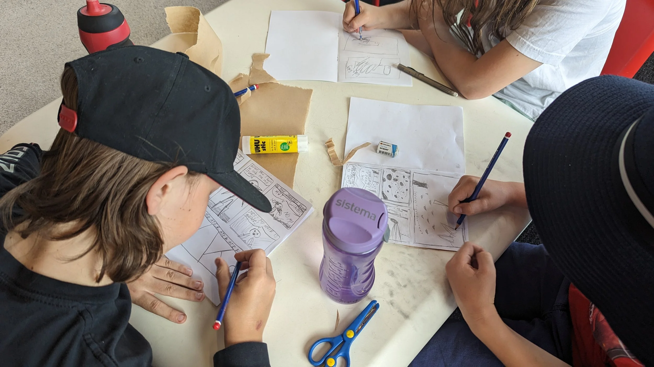 A small group of children and young people are drawing and creating comics in a workshop
