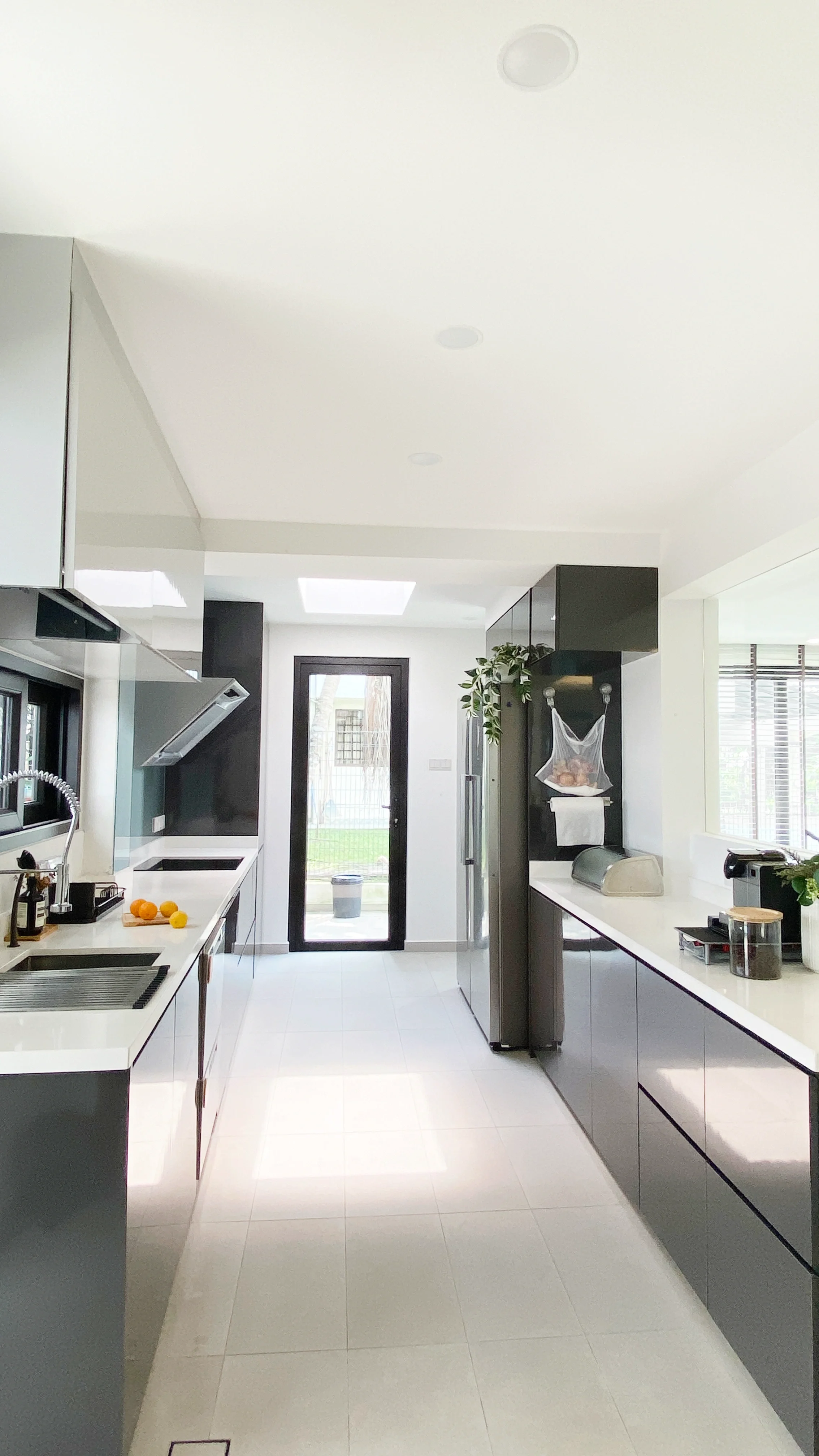 Modern kitchen with white and black cabinets, a black door leading outside, and various kitchen appliances on white countertops.