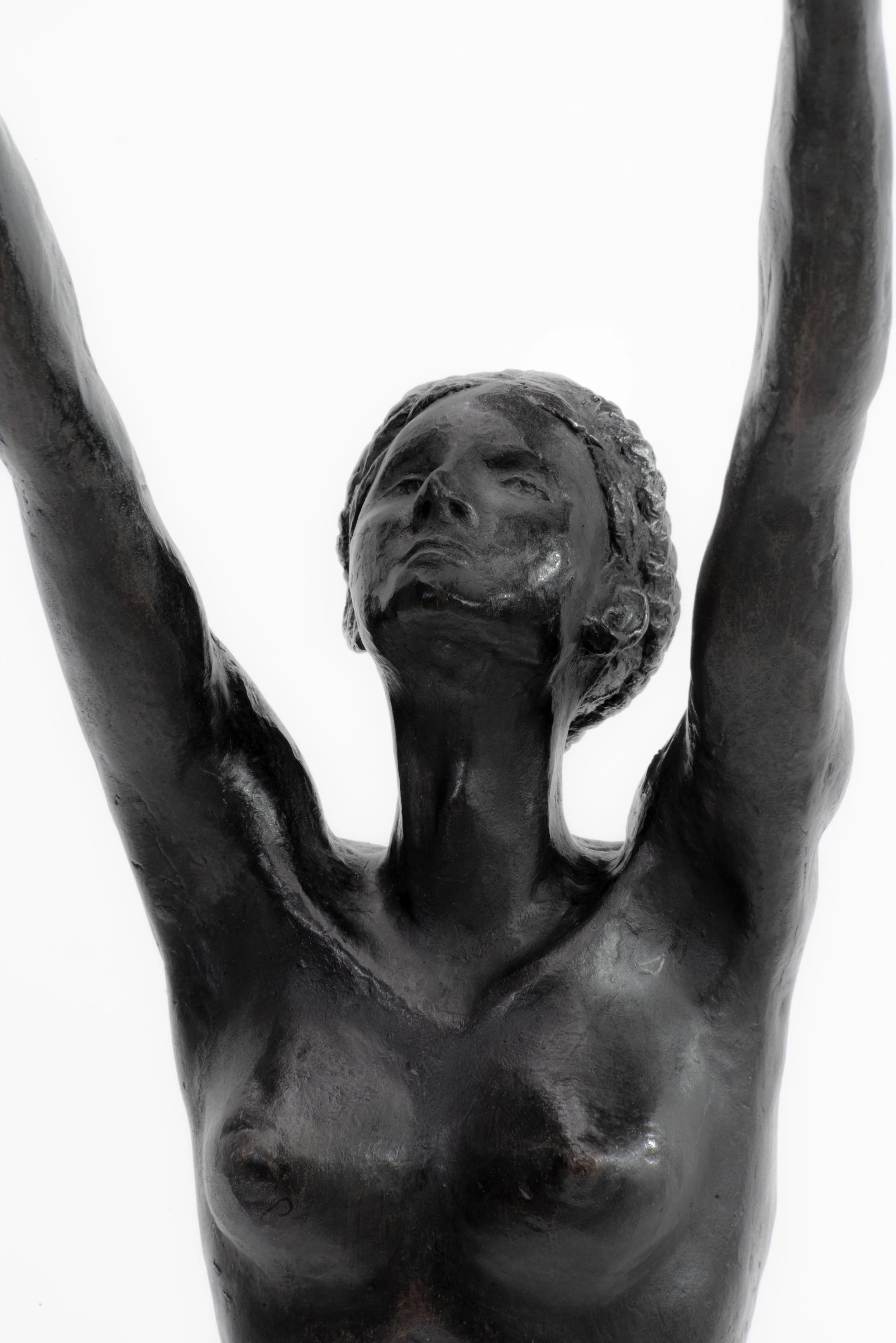 Black sculpture of a woman with arms raised, looking upward, against a white background.