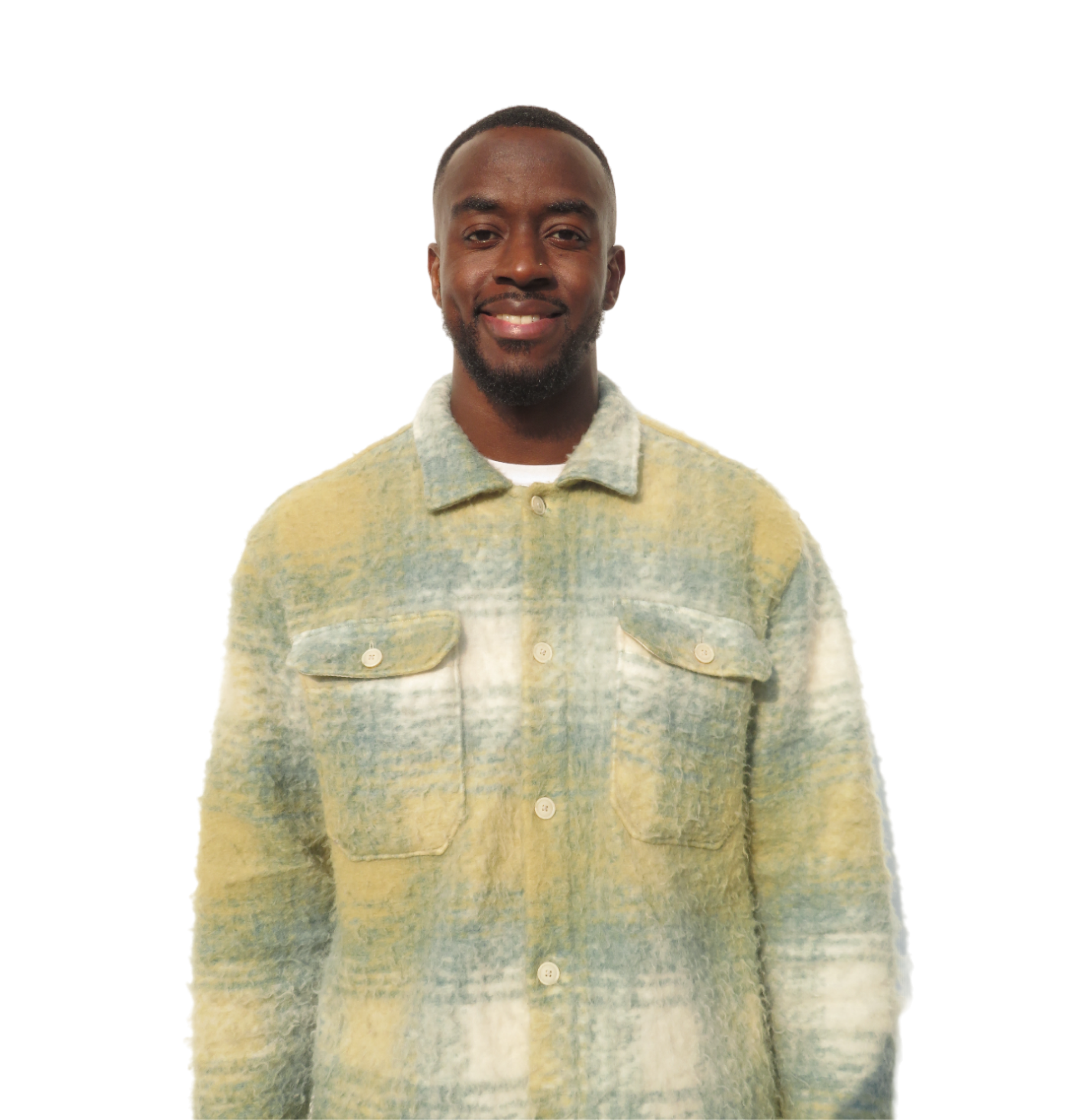 Een glimlachende jonge man met kort haar en een baard, gekleed in een lichtgekleurde, gestructureerde blousejas met zakken, staand tegen een witte achtergrond.