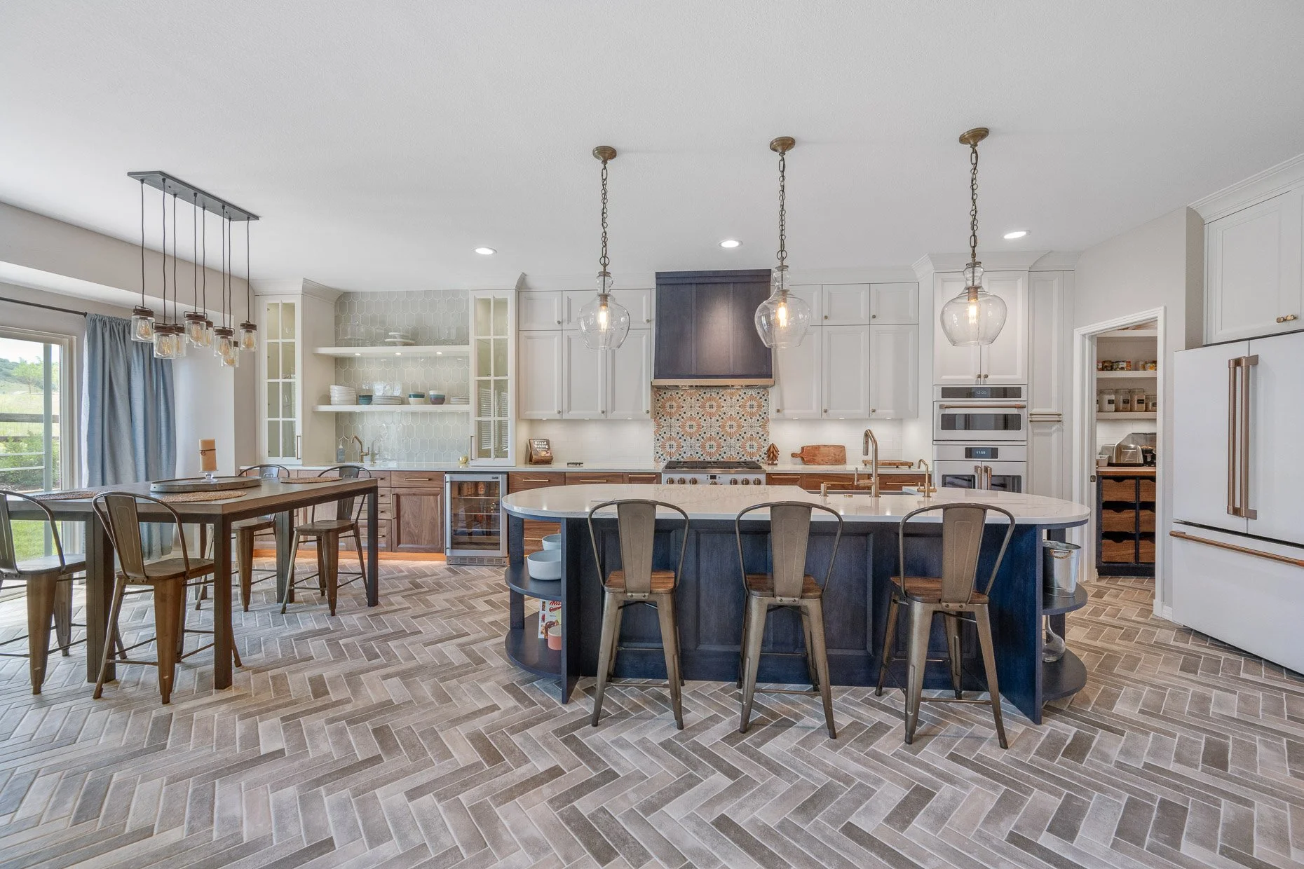 Gorgeous kitchen design with herringbone floor design, Cafe Appliances, center island, Moroccan tile backsplash and dark blue accents.