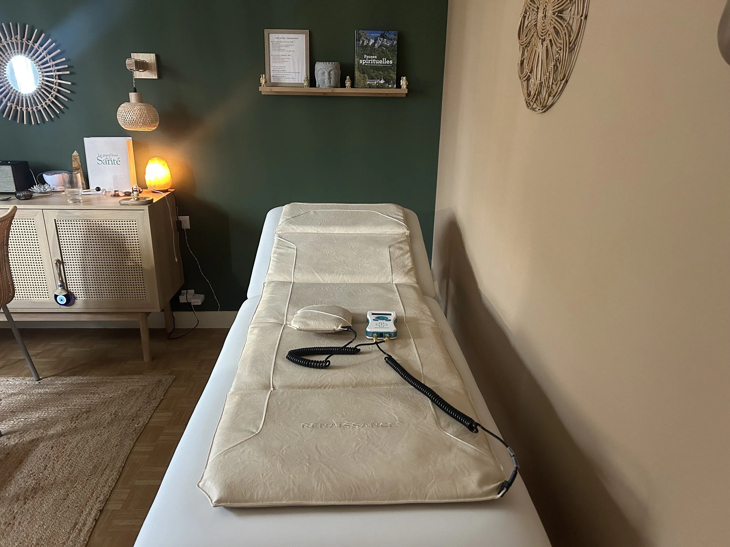 Un lit d'hôpital avec un tapis à côté, sur le lit repose un appareil médical connecté avec des câbles.