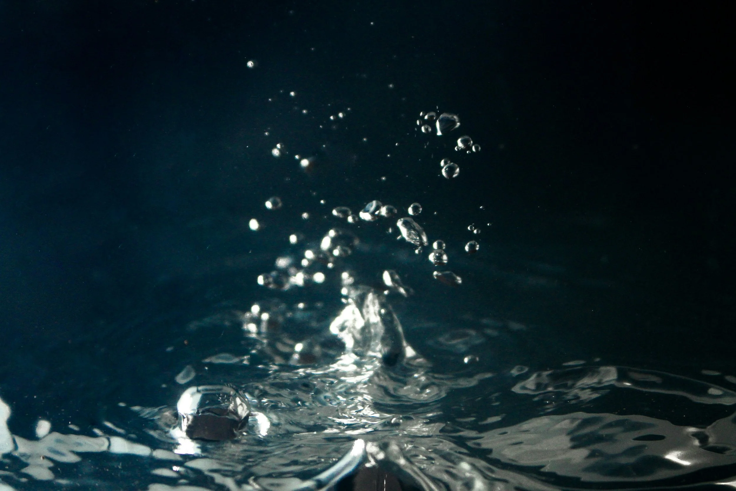 Close-up of water droplets splashing on a dark surface.