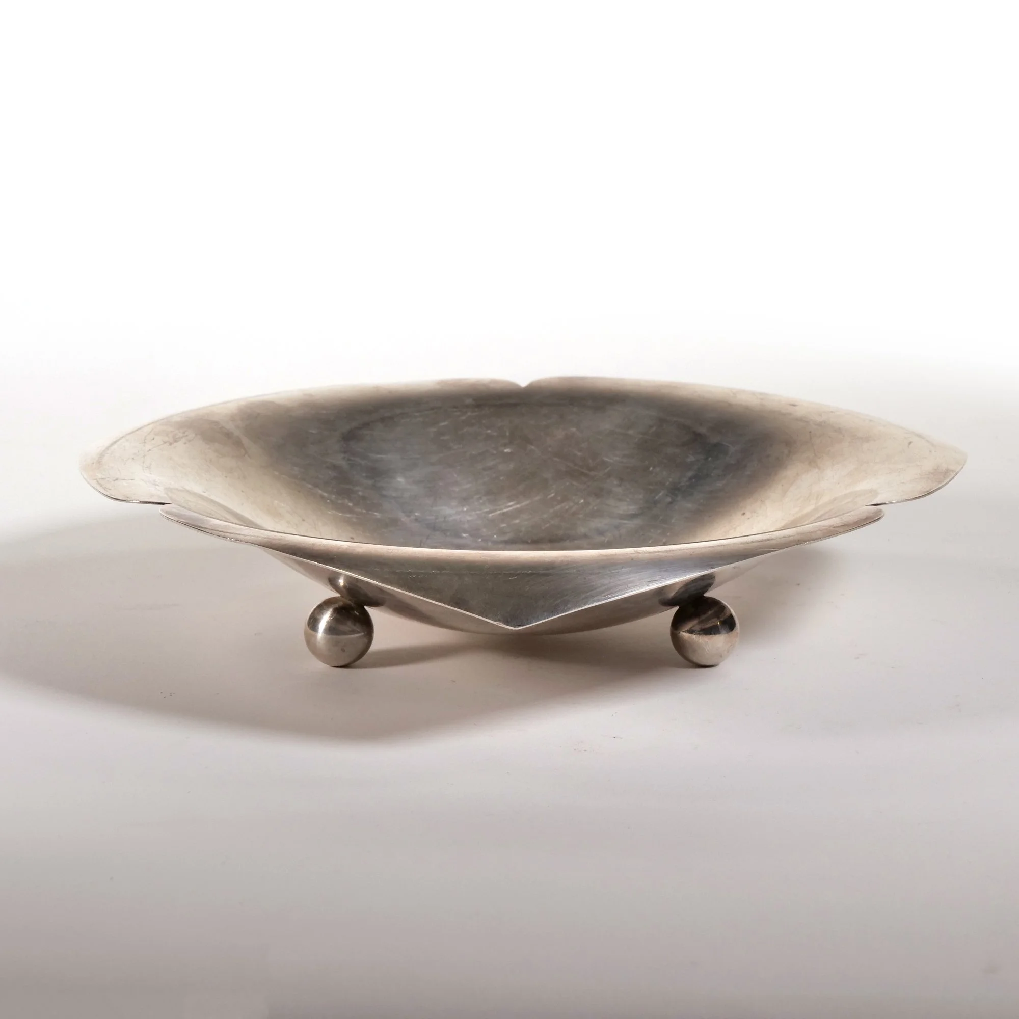 Metal decorative bowl with spherical feet, shallow and wide, on a plain white background, auctioned and photographed by ACES Gallery.