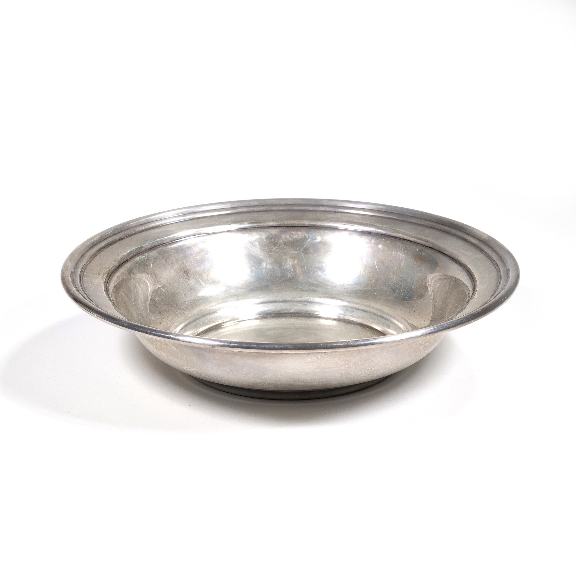 A shiny, round sterling silver bowl with a wide rim, placed on a white background, auctioned and photographed by ACES Gallery.