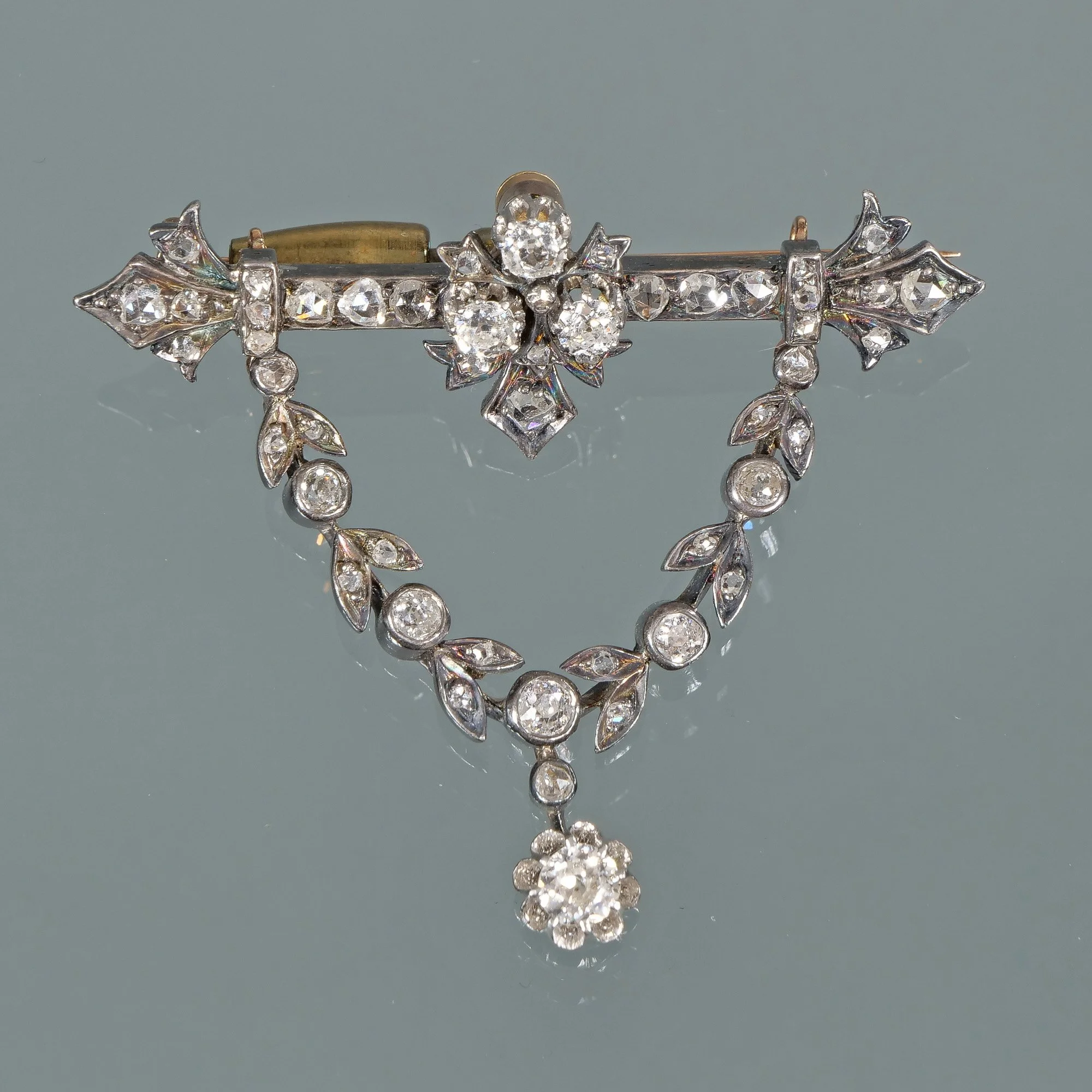 Vintage silver-toned brooch with leaf and floral design, decorated with clear rhinestones or diamonds, featuring a dangling floral cluster at the bottom, auctioned and photographed by ACES Gallery.